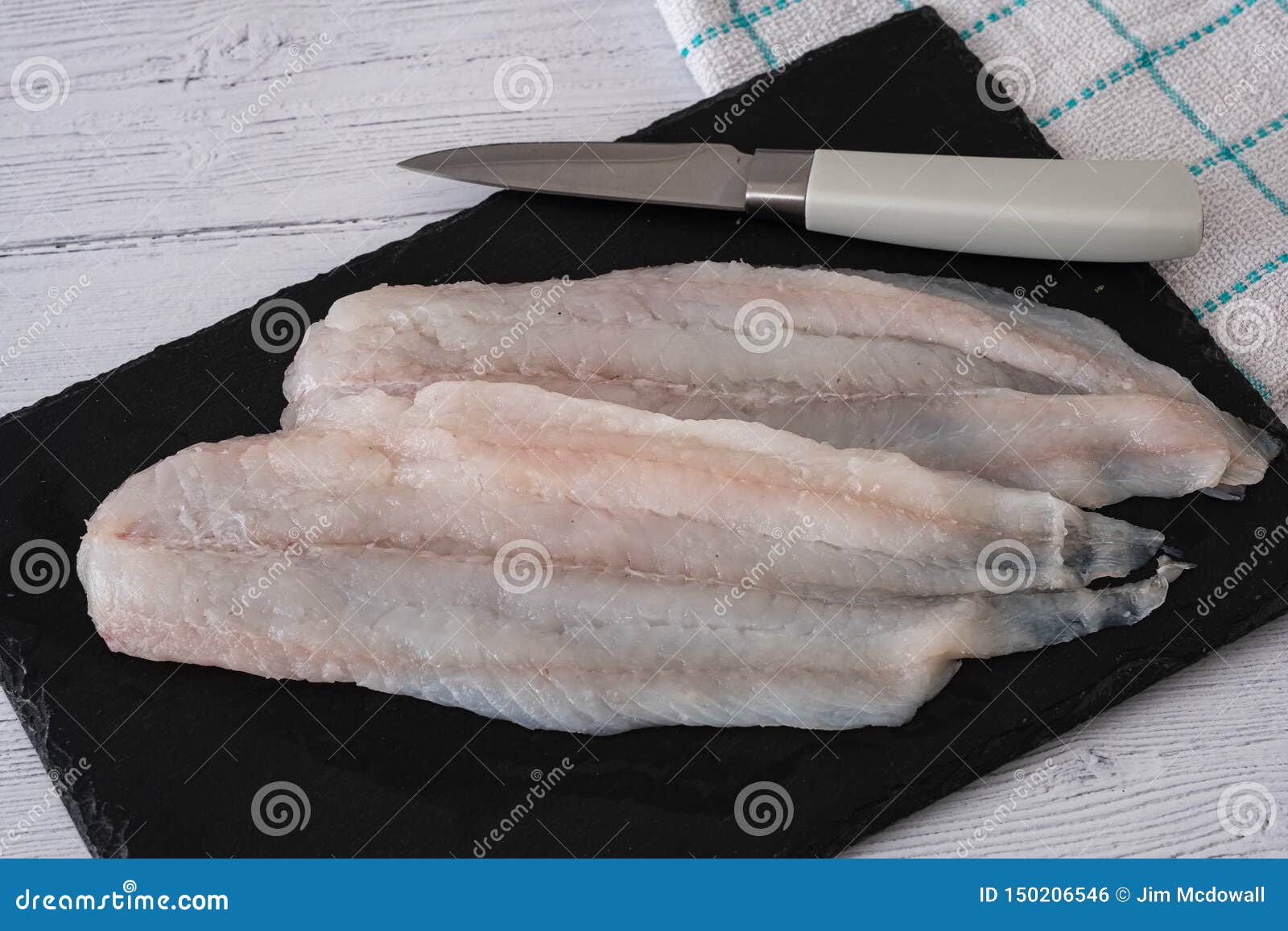 filleted scottish haddock on a carving slate and ready for the oven