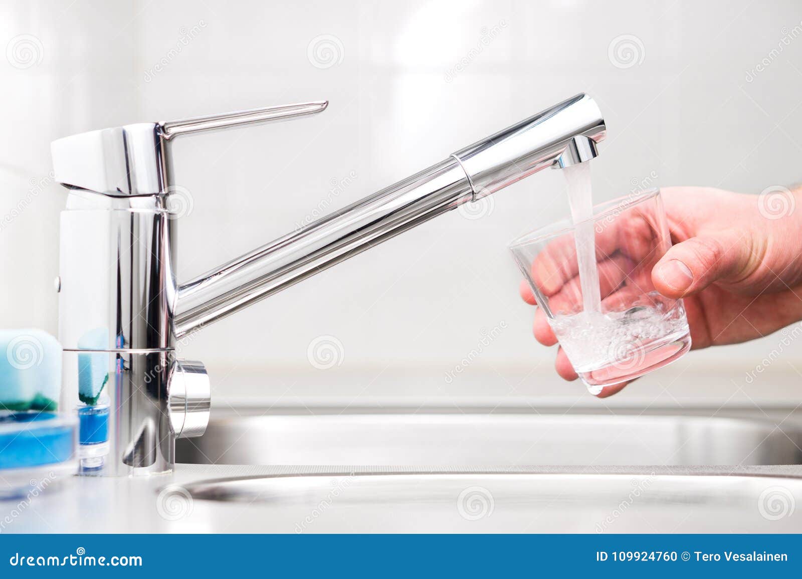 filling glass with tap water. modern faucet and sink.