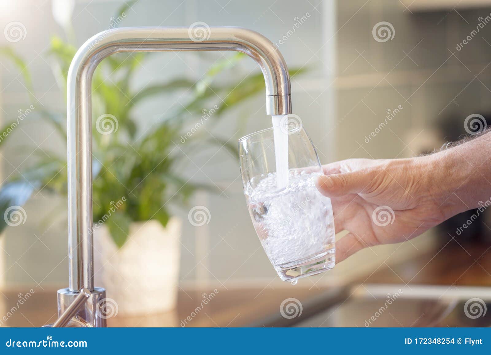 filling up a glass with drinking water from kitchen tap