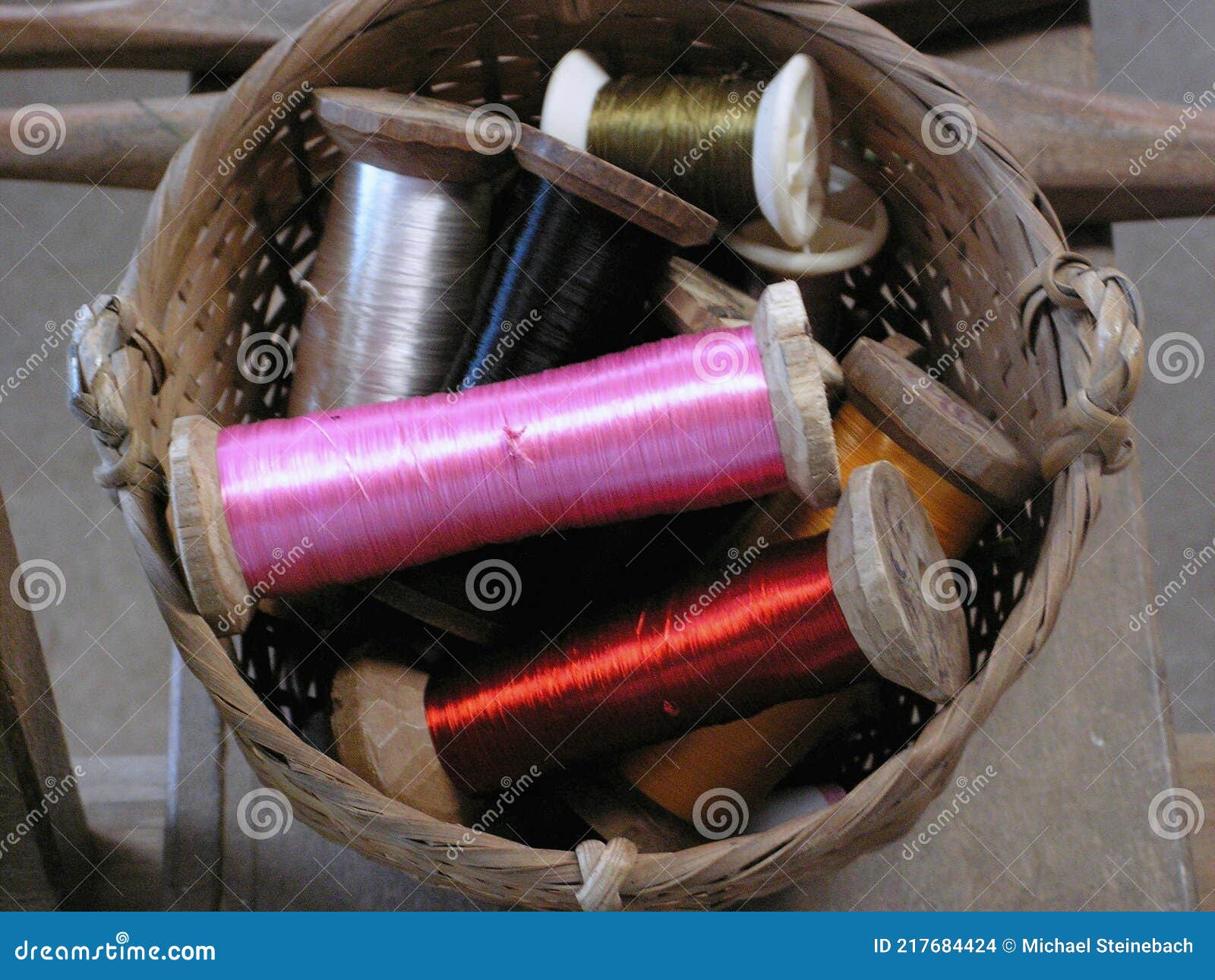a small basket with several colorful silk yarn bobbins