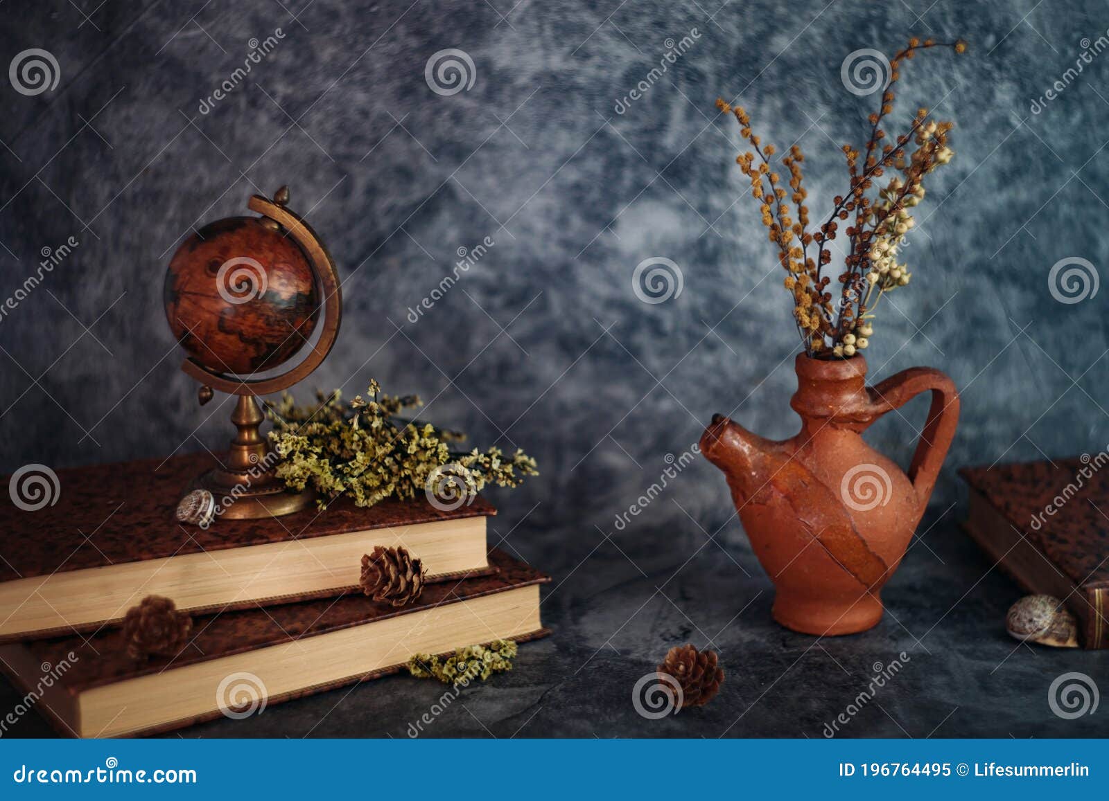 fineart concept shot. stilllife with rustic books  with flowers and globe on grey backgrouns