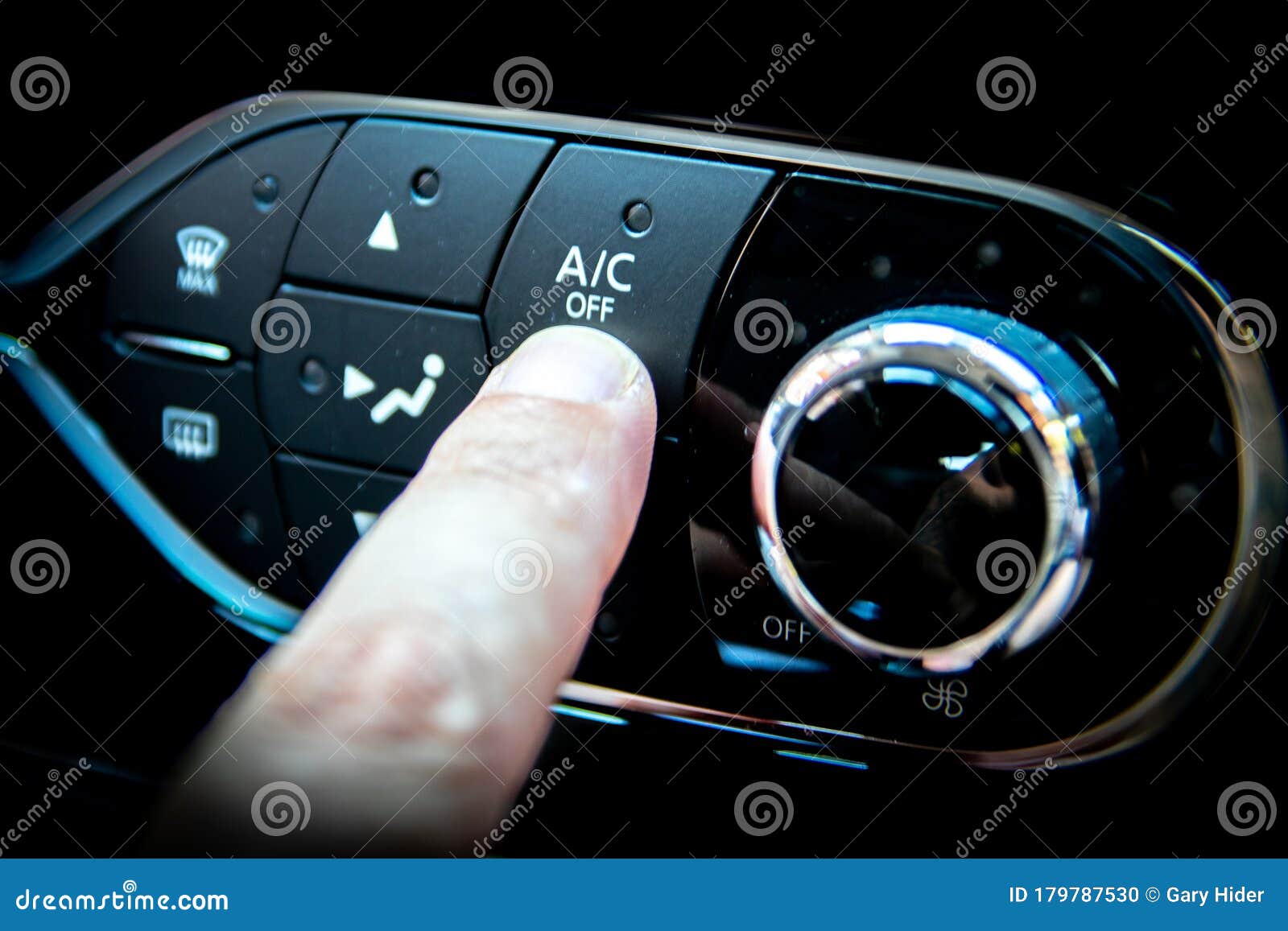 a finger pressing the a/c or air conditioning button on the dashboard of a car