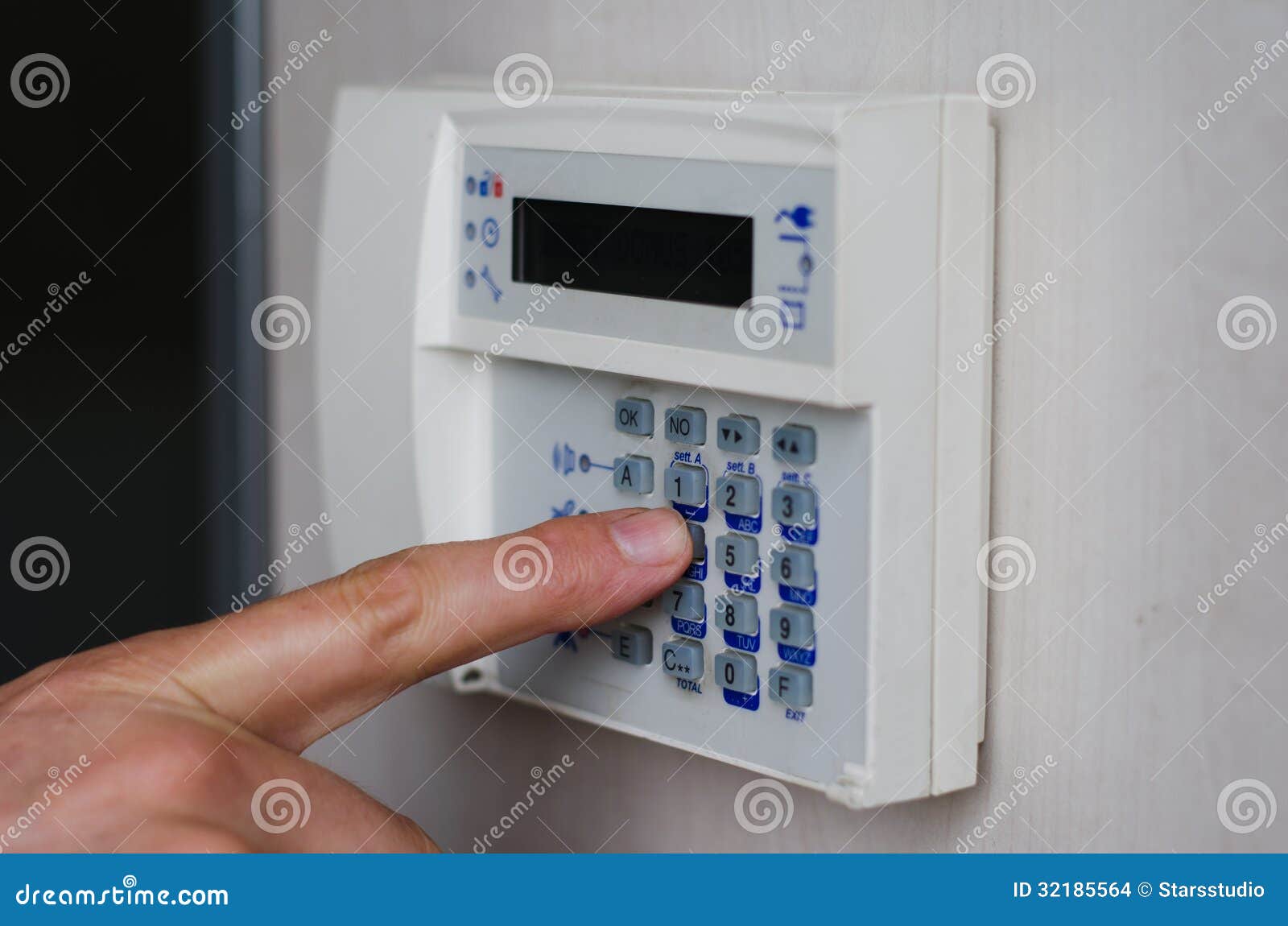 Finger pressing keys on alarm keypad. Finger setting security alarm, pressing keys on keypad