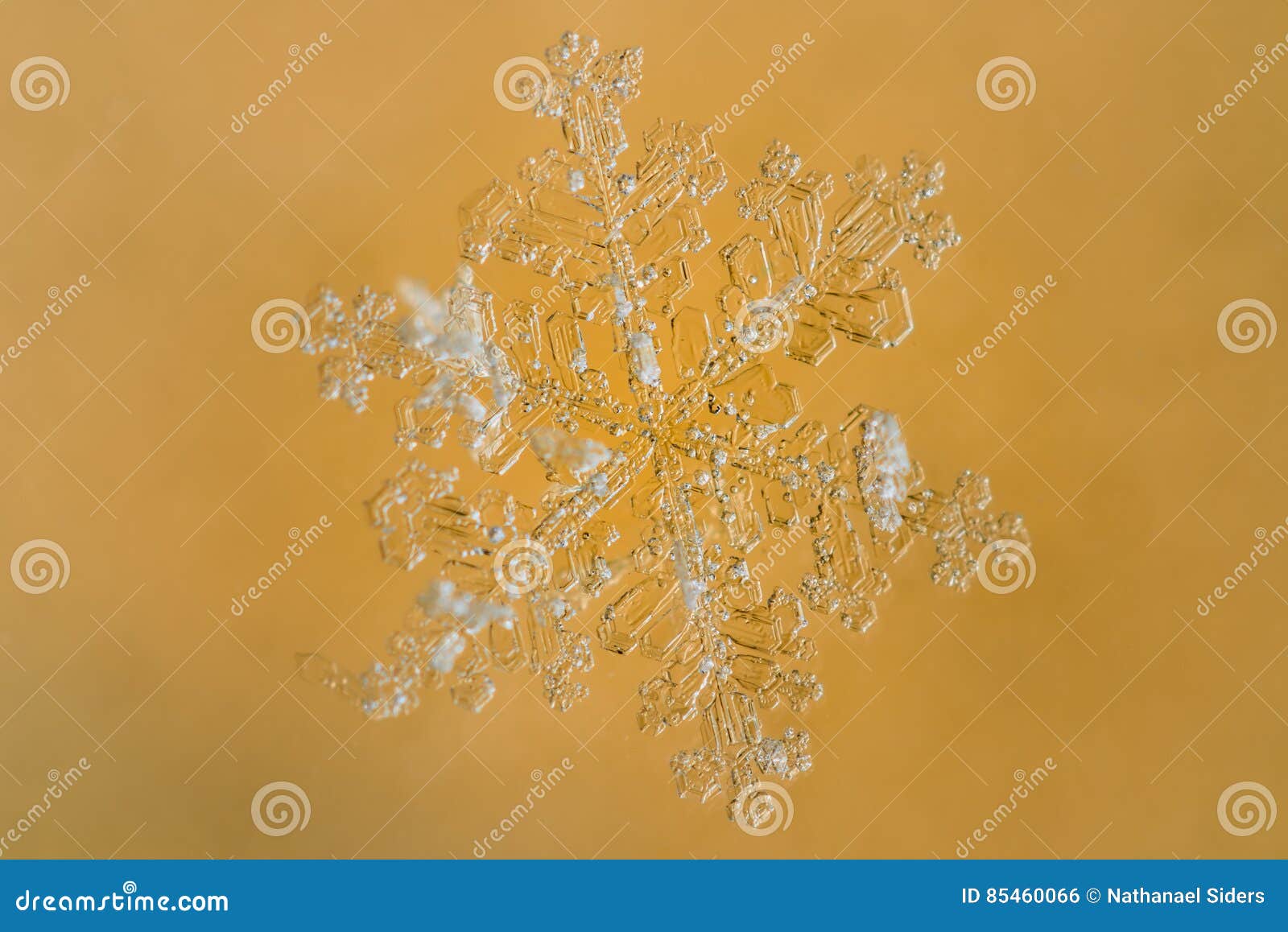 Fiocco di neve con fondo giallo. Immagine del primo piano di un fiocco di neve con un fondo giallo