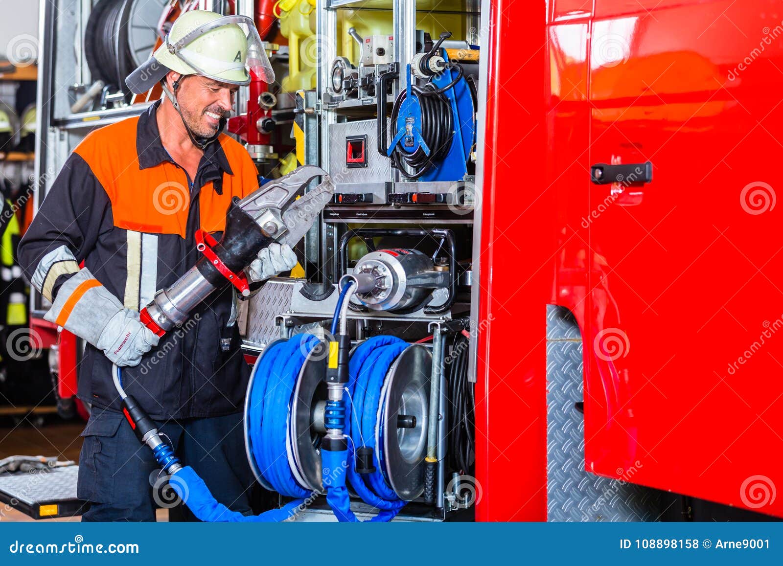 Fire Fighter Checking Hydraulic Cutter at Fire Engine Stock Photo