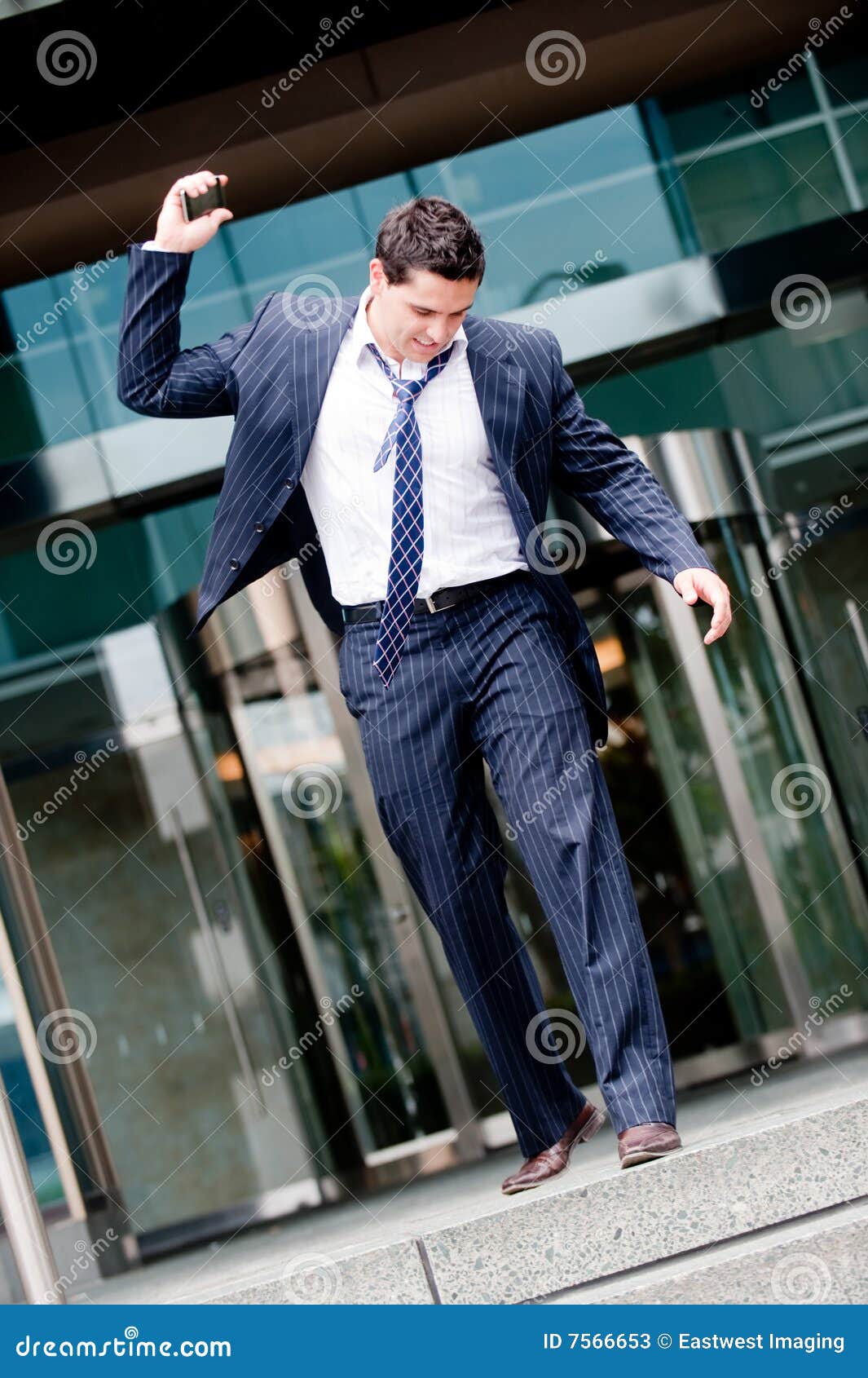 Fired. A young businessman walking out of building about to smash phone