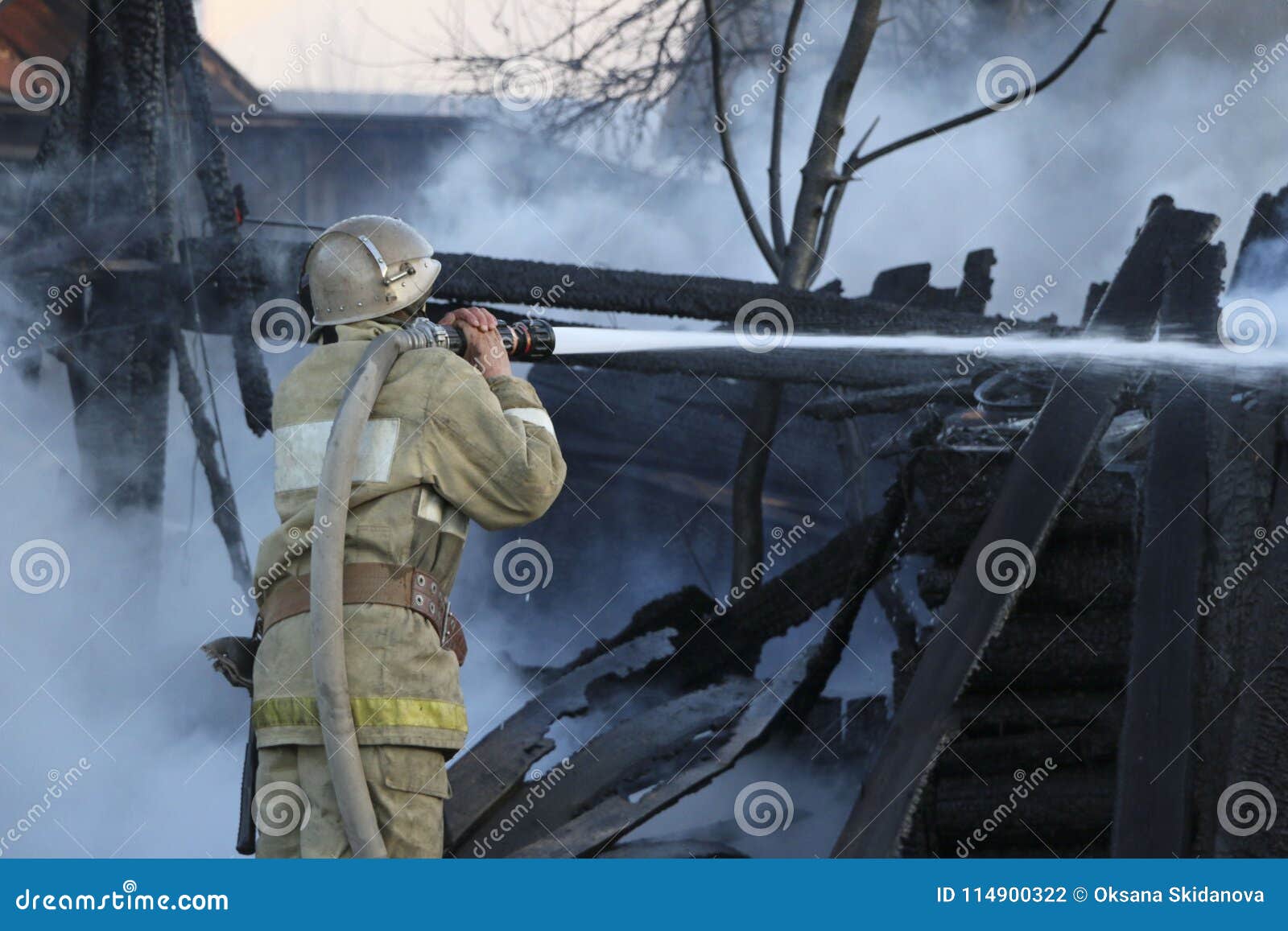 firefighter extinguishes the fire. fireman holding a hose with water, watering a strong stream of burning wooden structure in the