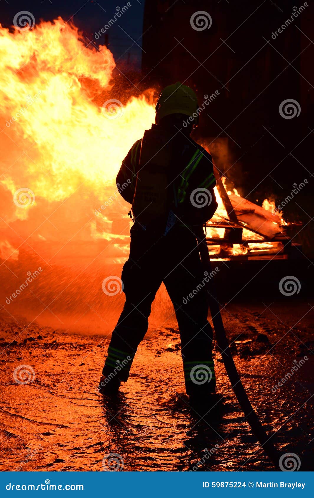 Firefighter Hoses Down a Fire Amid Strong Flames Stock Photo Image of
