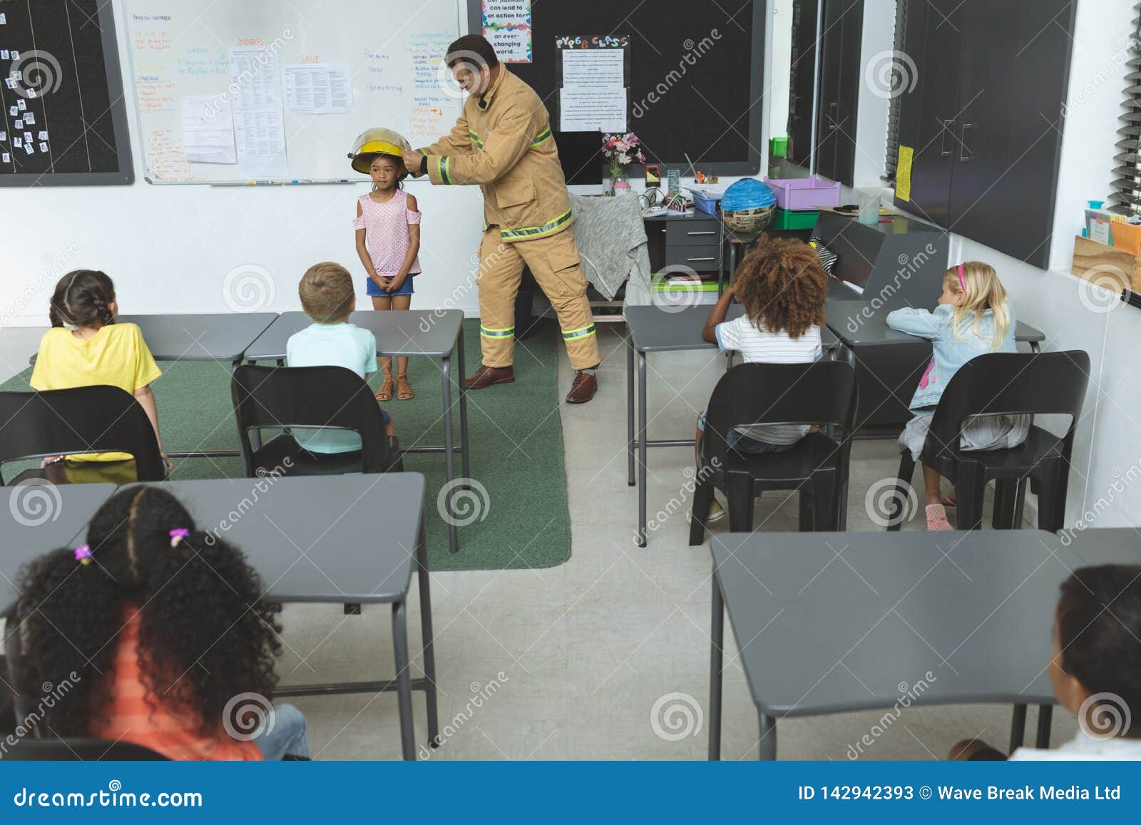 Firefighter Teaching Student about Fire Safety in Classroom Stock Image