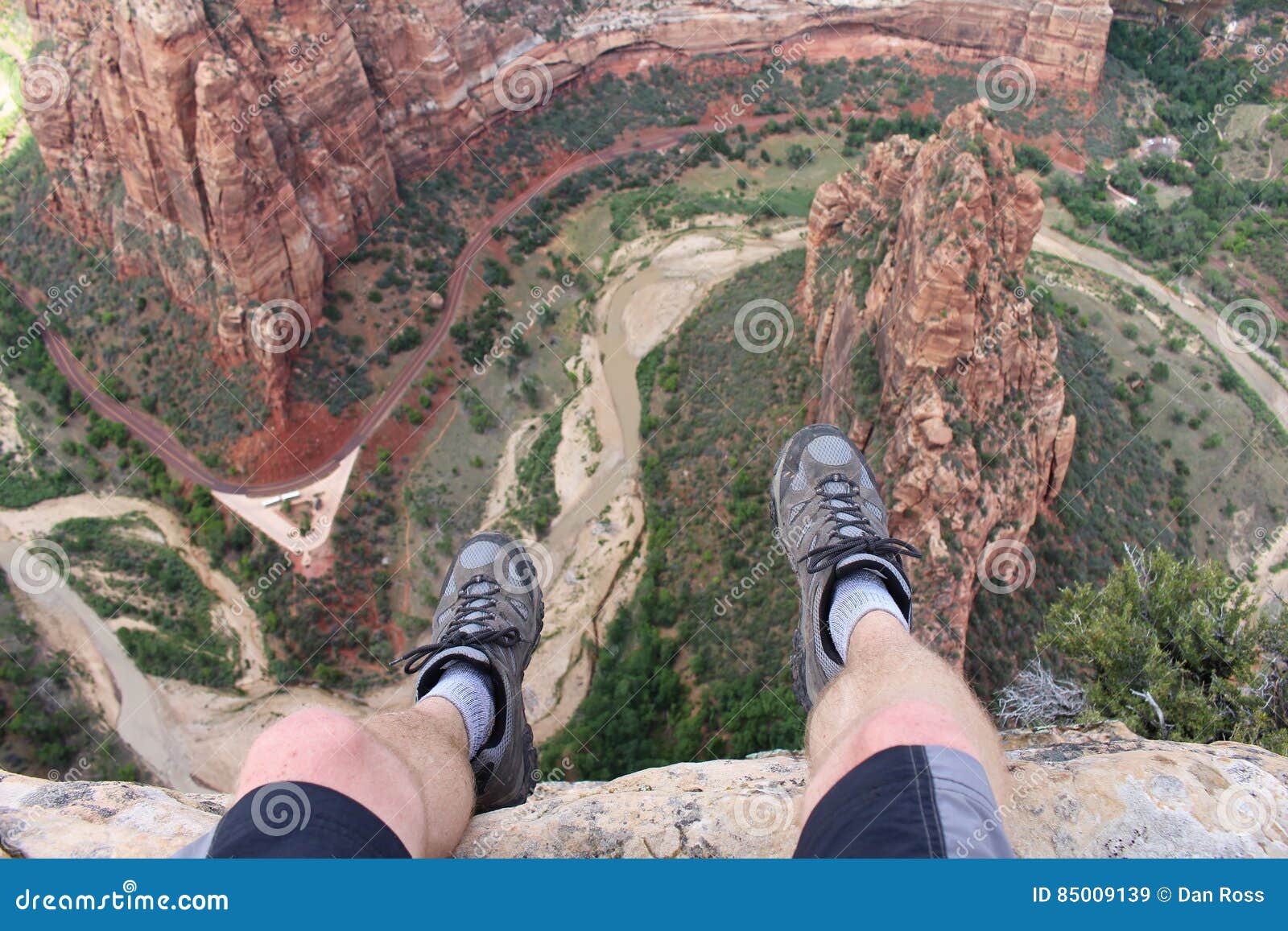 first person perspective shot from a hiker sitting at the edge of a cliff in zion national park.