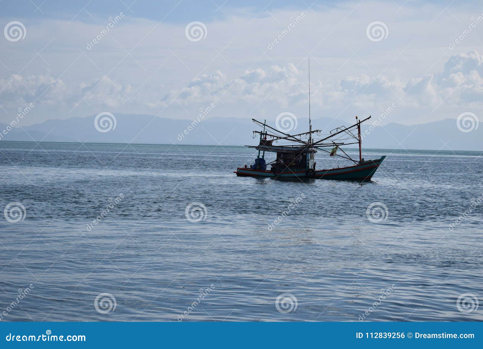 Fischer ` s Boot, Koh Tao. Ein lokalisiertes kleines Fischerboot im Golf von Thailand unweit von Koh Tao auf einem klaren Meer mit Bergen und Wolken im Hintergrund