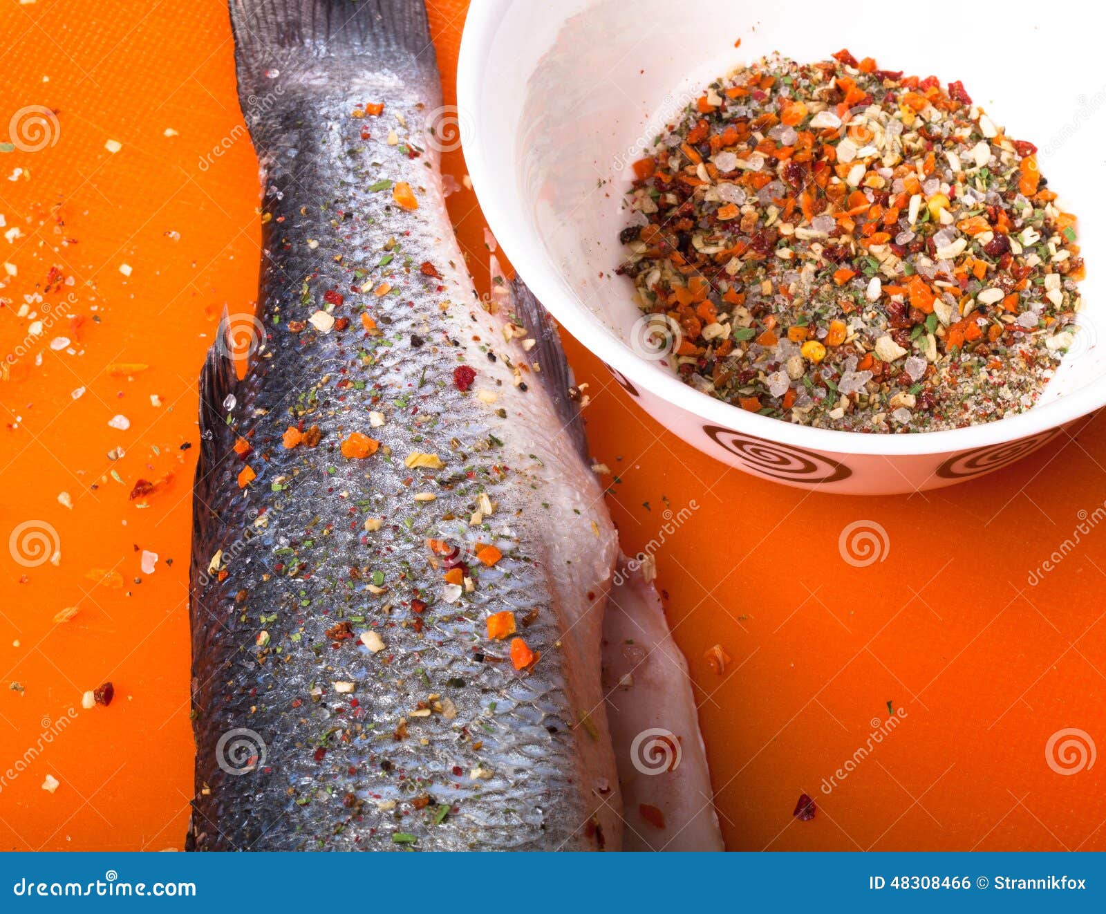 Fish and Spices on a Plastic Cutting Board. Fish in the Process