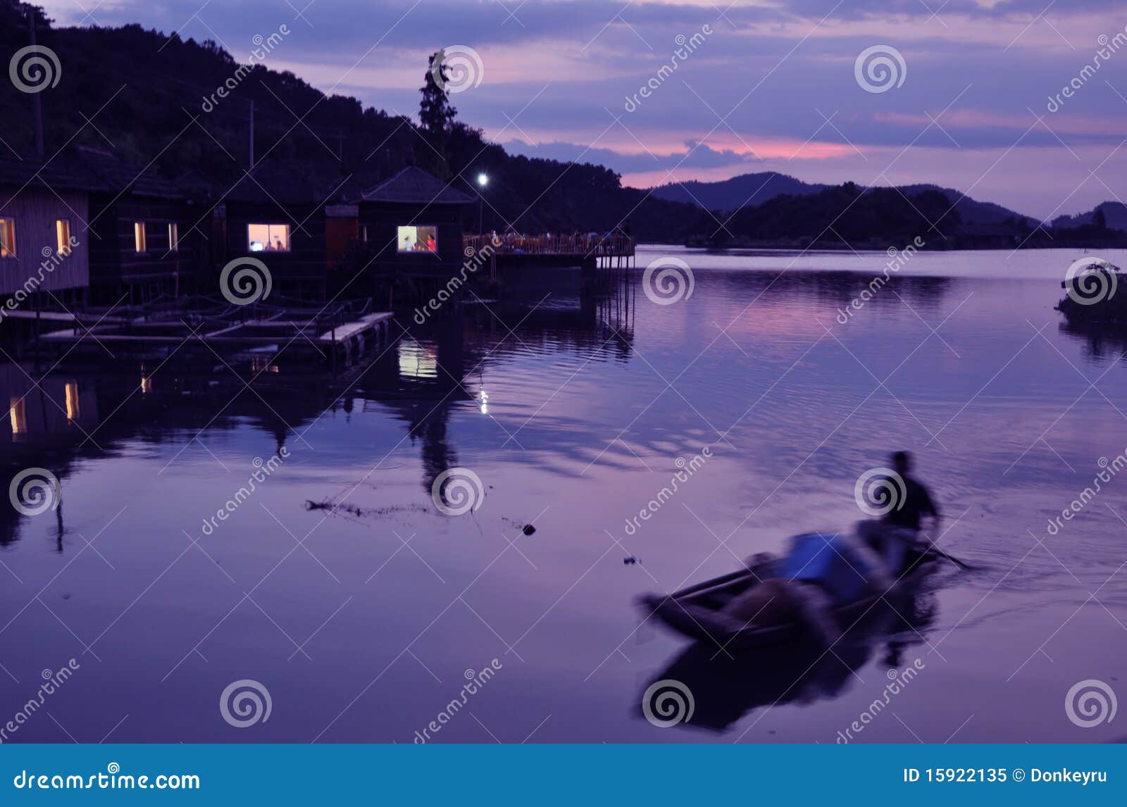 Fishboat в озере захода солнца. Рыболов гребет fishboat в озере в Гуанчжоу, перепаде захода солнца реки перлы, Guangdong, Китае.