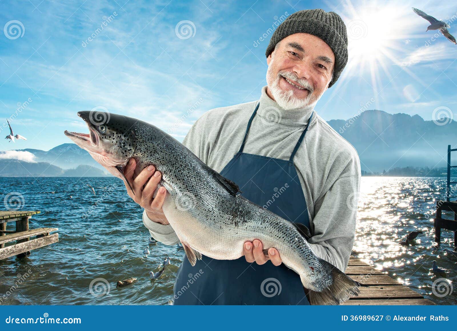 Fisher que sostiene un pescado grande del salmón atlántico en el puerto pesquero