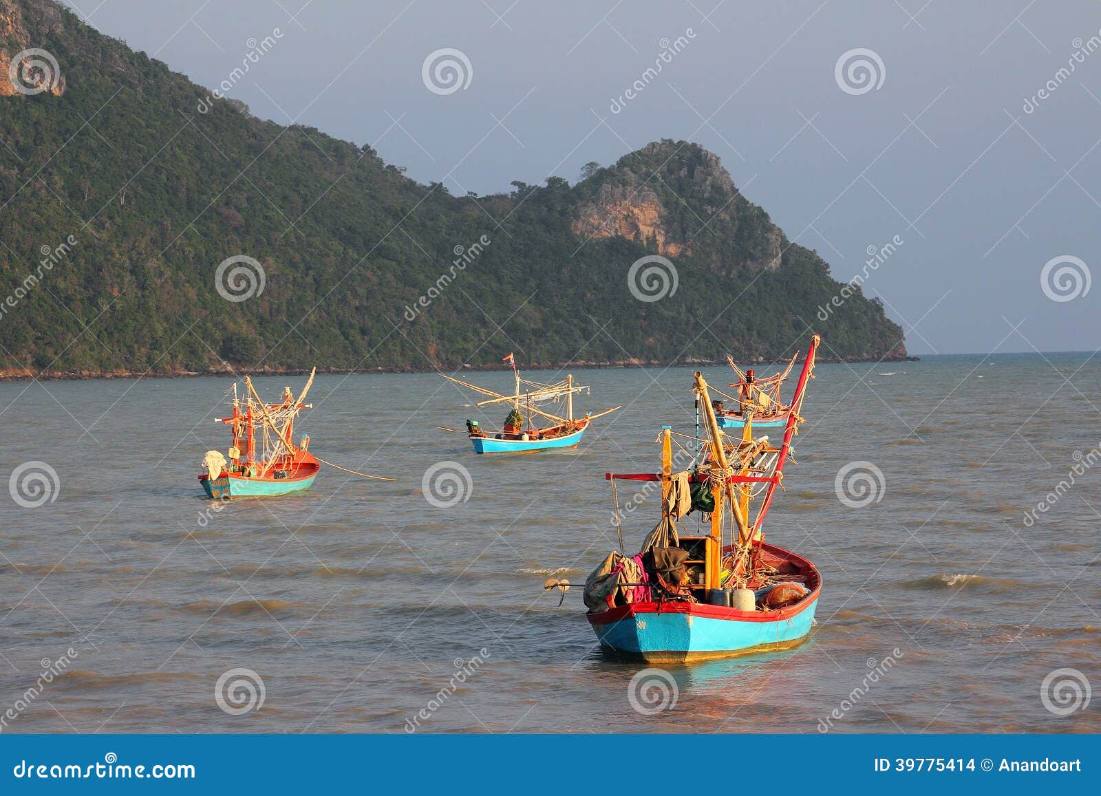 Fisherboats i aftonljuset. Tre coloful fisherboats svävar i havet, i Thailand nära Prachuab. Fartygen tänds av det varma ljuset av aftonsolen. I bakgrunden är en ö.