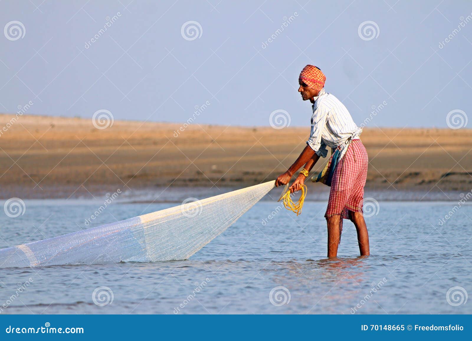 A Fisherman Catches Fish by Traditional Hand Net in India