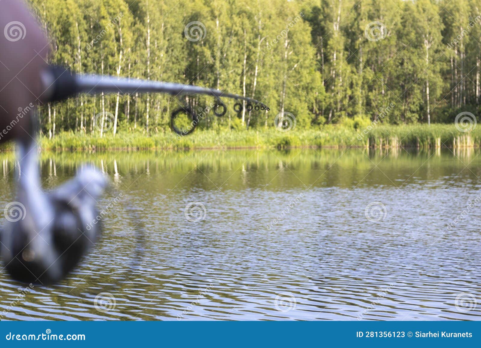 A Fisherman with Fishing Rods, a Spinning Reel on the River Bank