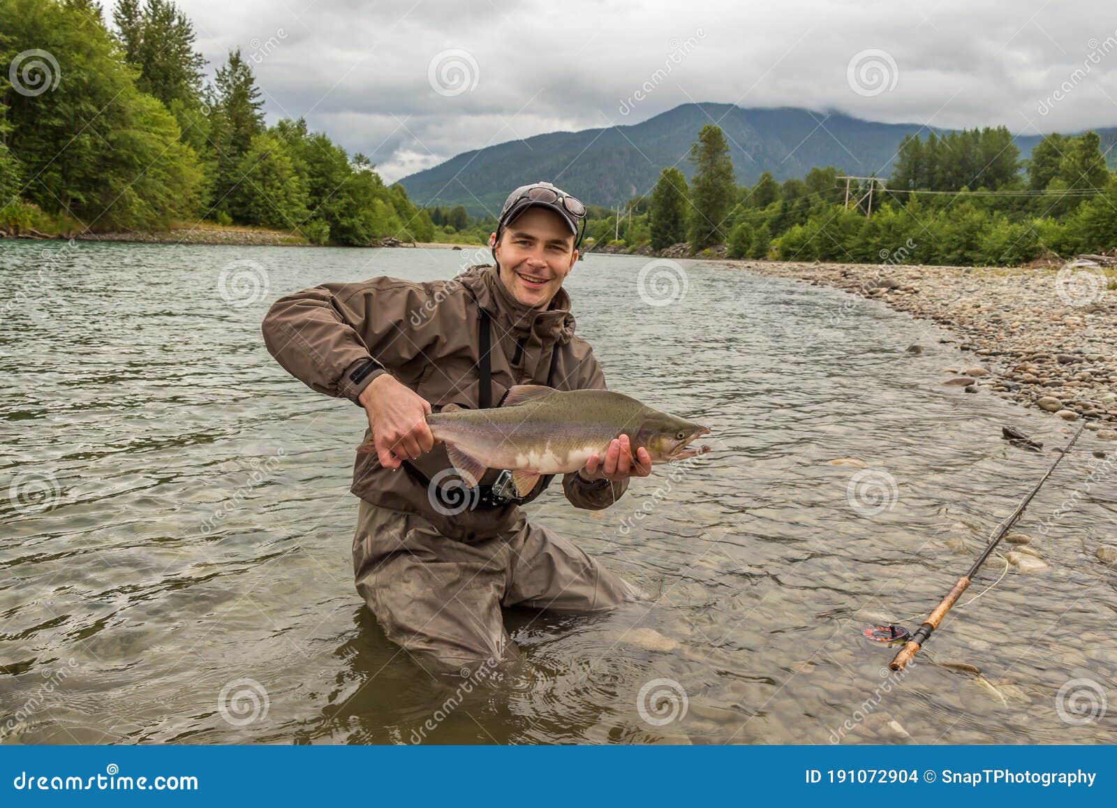 a fisherman holding a huge taimen trout caught on a river in mongolia, moron, mongolia