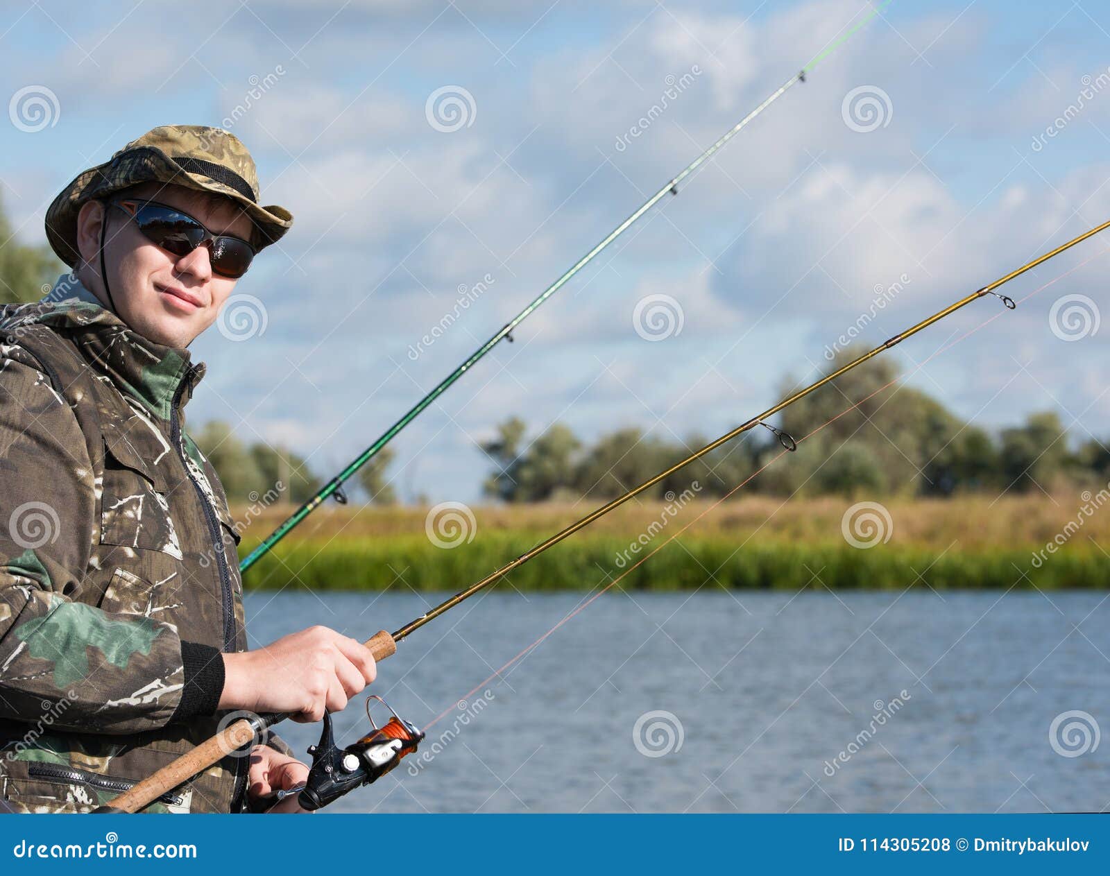 A Fisherman with a Spinning Rod To Catch Fish. Sunglasses and