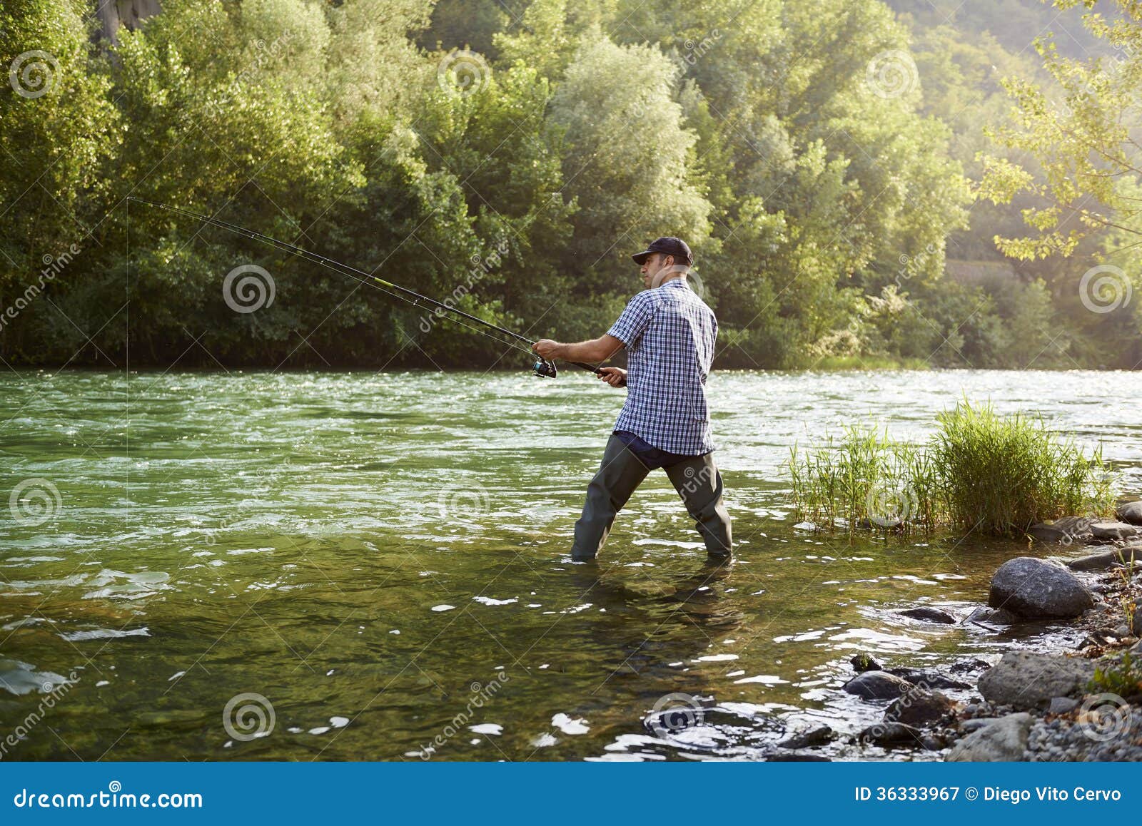 Fisherman Standing Near River and Holding Fishing Rod Stock Image