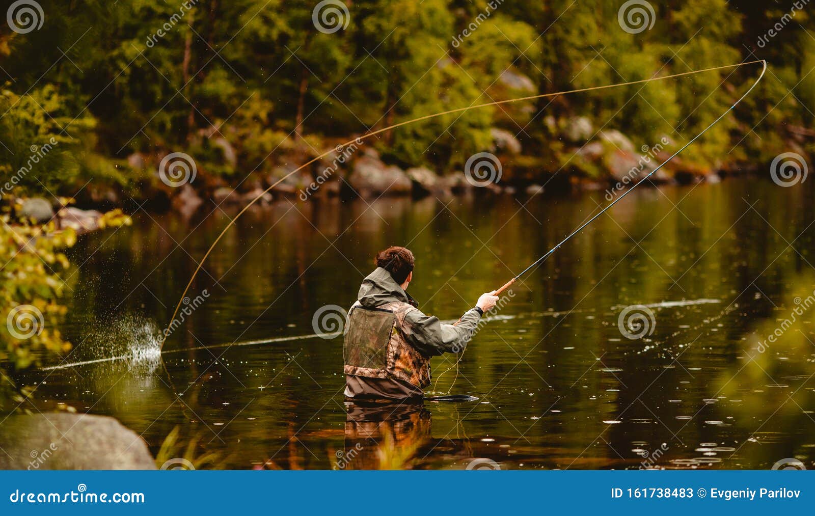 fisherman using rod fly fishing in mountain river