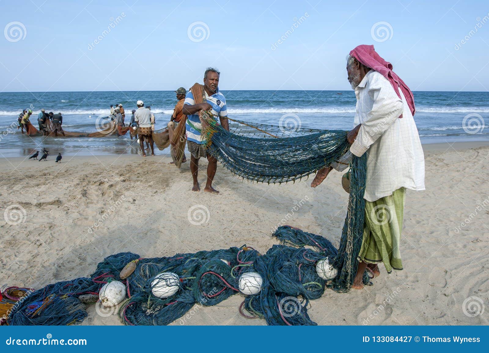 Fishermen Drag a Large Fishing Net Onto the Beach. Editorial