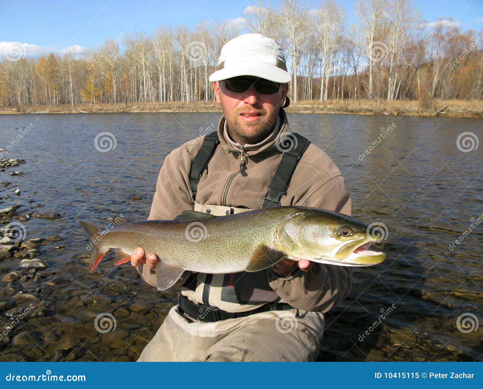 Young handsome brutal caucasian man in casual outfit fishing on a