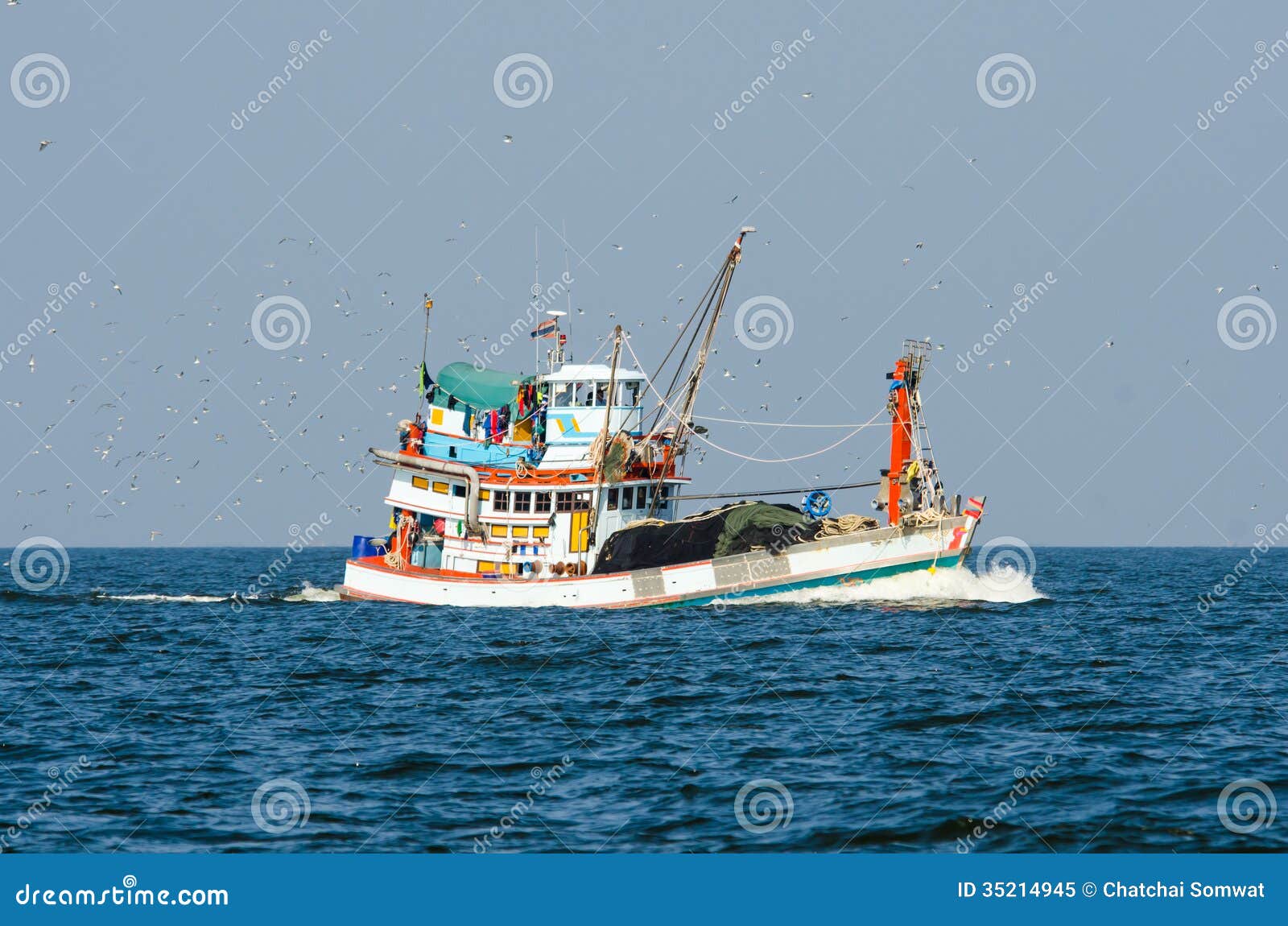 Fishing boat trawler in the Gulf of Thailand and birds following.