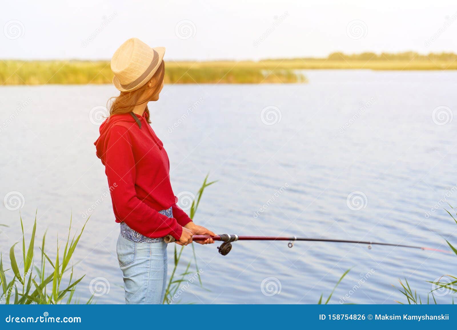 Fishing with Fishing Rod Standing on Shore of Lake Stock Photo