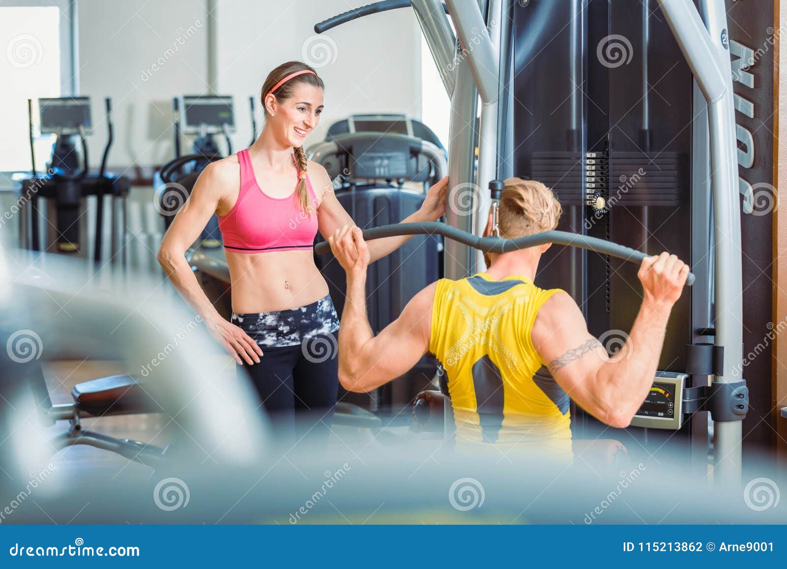 fit beautiful woman smiling with admiration at a strong man in the gym