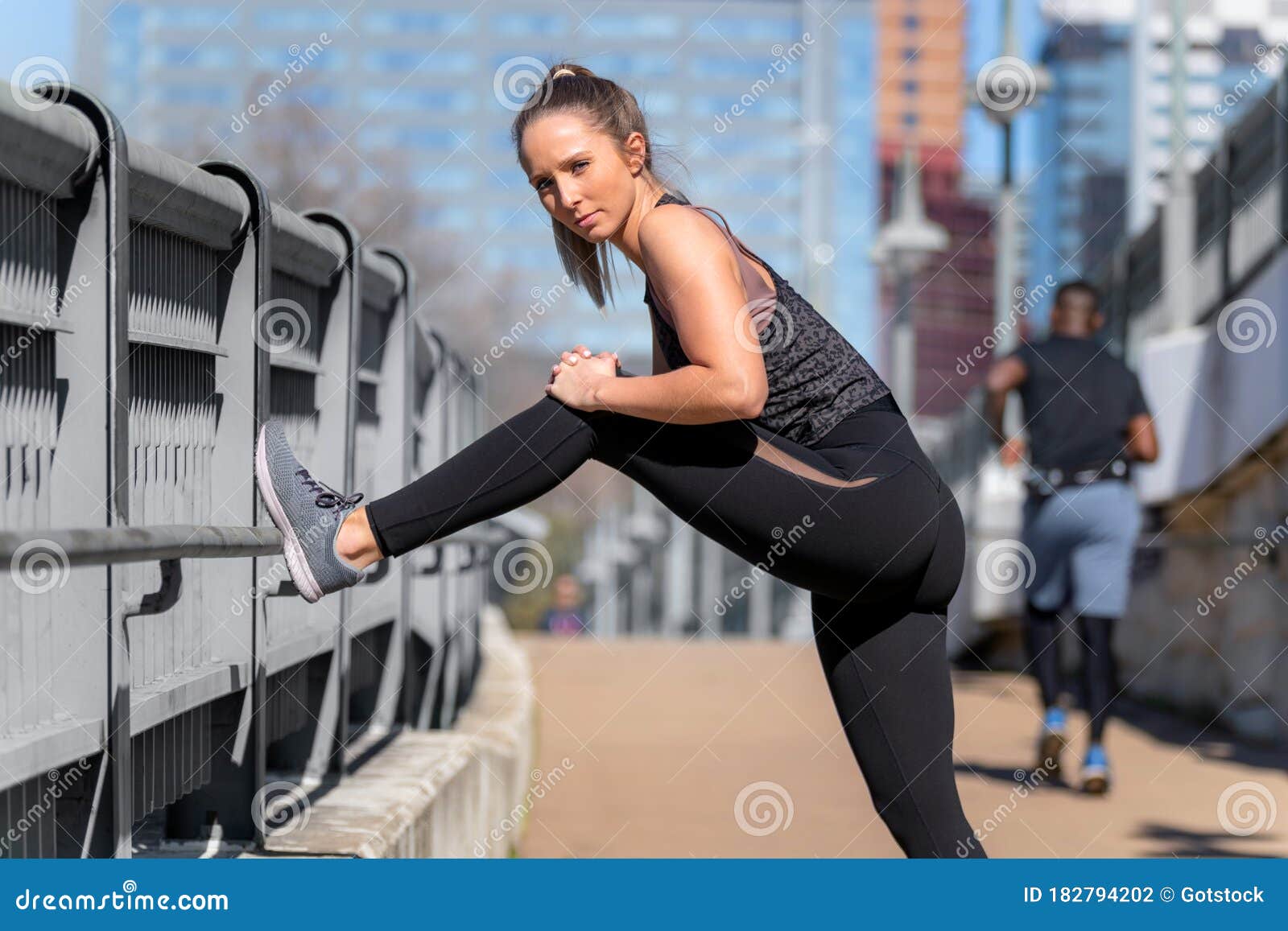 Fit Female Athlete Runner with Toned Legs and Stretches during Urban ...