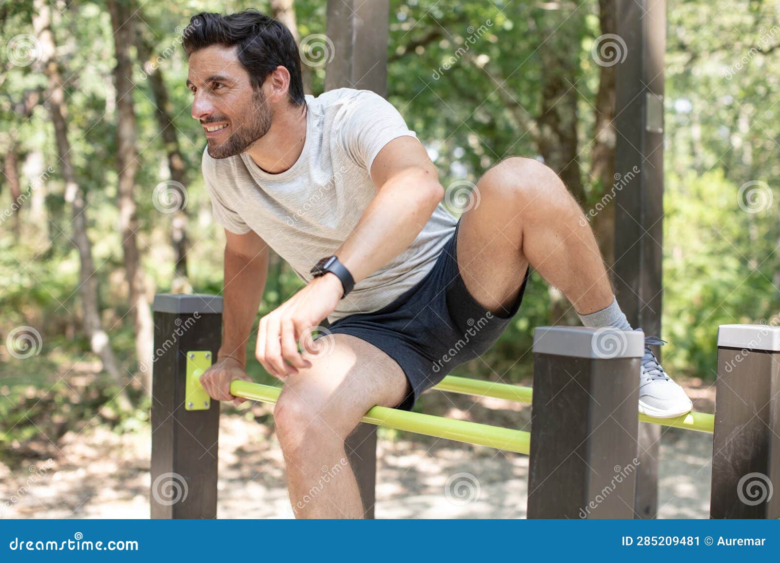 fit man doing exercises in forest outdoor gym using bars