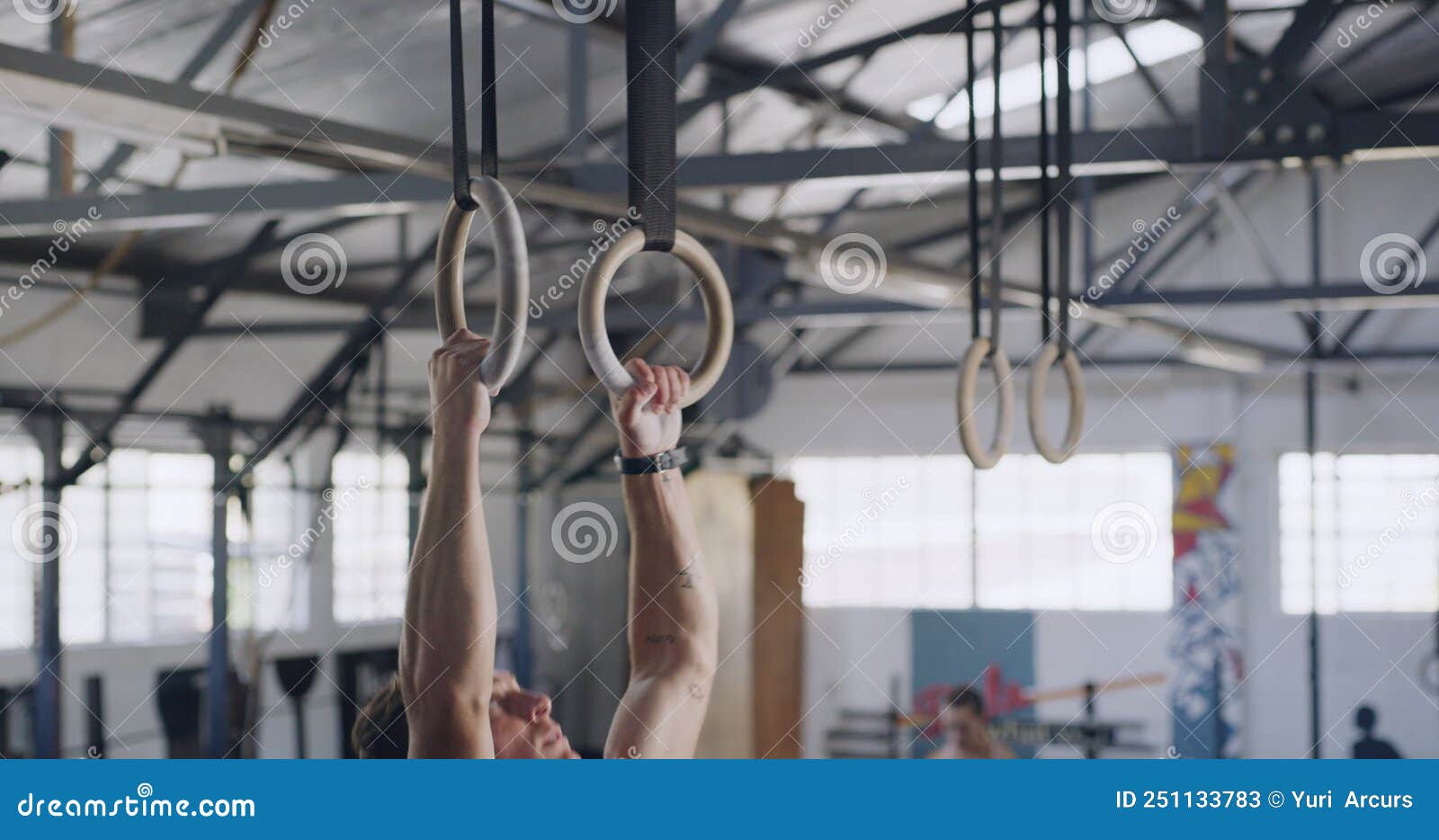 Fit Man Using Gymnastic Rings for Pull Ups for Training Exercise in a
