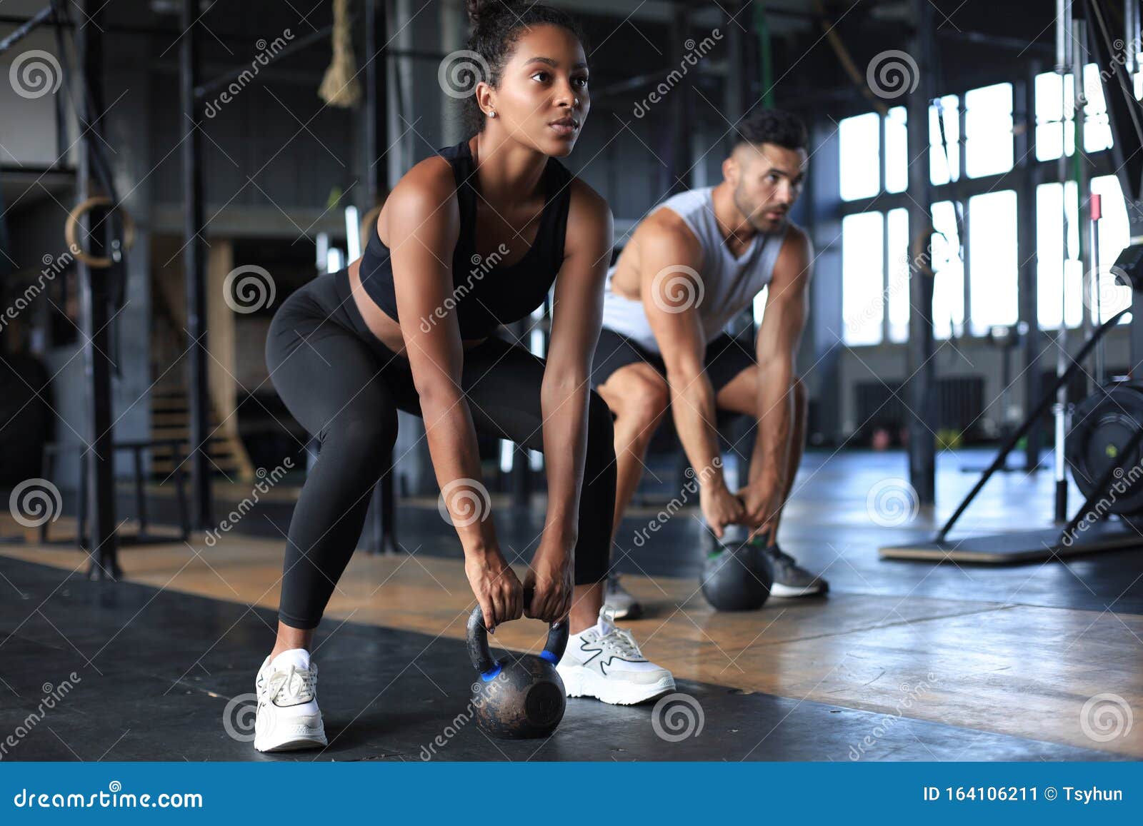 fit and muscular couple focused on lifting a dumbbell during an exercise class in a gym