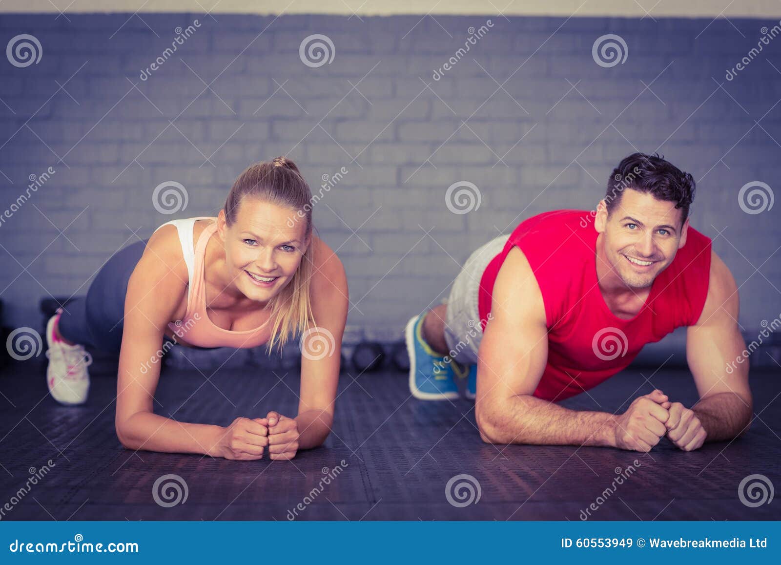 fit smiling couple planking together in gym