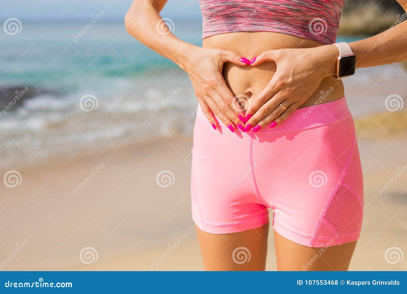 fit woman showing hands heart sign on her stomach