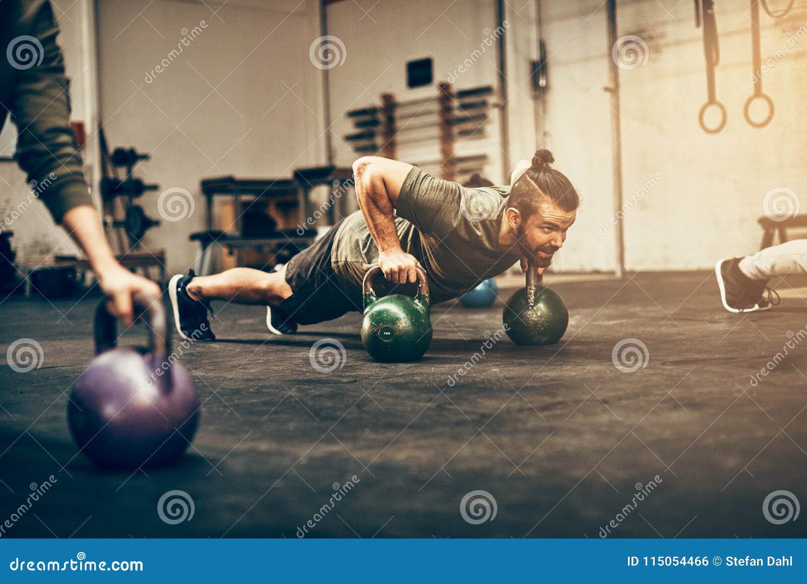 fit young man planking with dumbbells at the gym