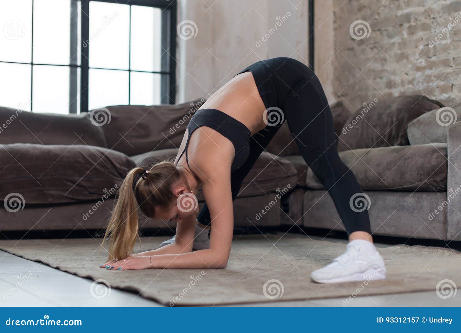 fit young sportswoman doing standing straddle forward bend or prasarita padottanasana pose. female athlete practicing