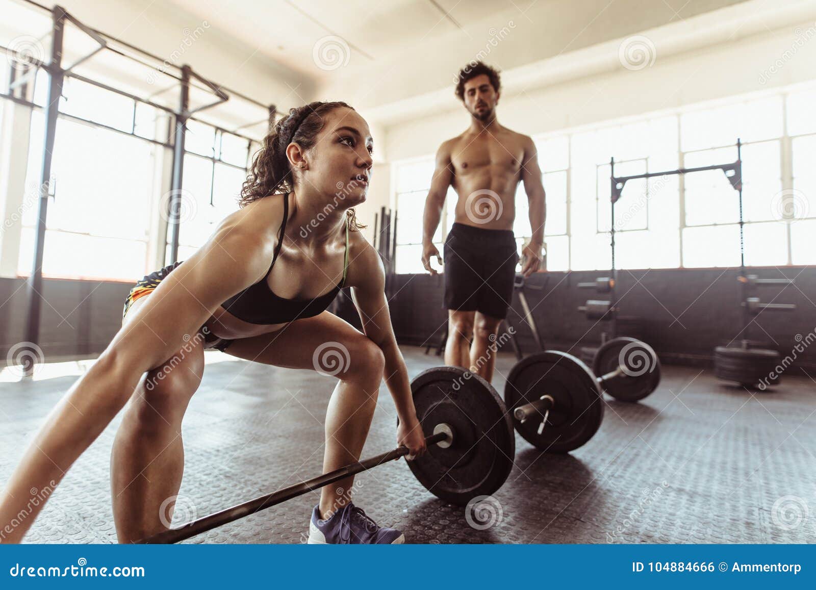 Tough young woman exercising with barbell. Determined female athlete  lifting heavy weights Stock Photo - Alamy