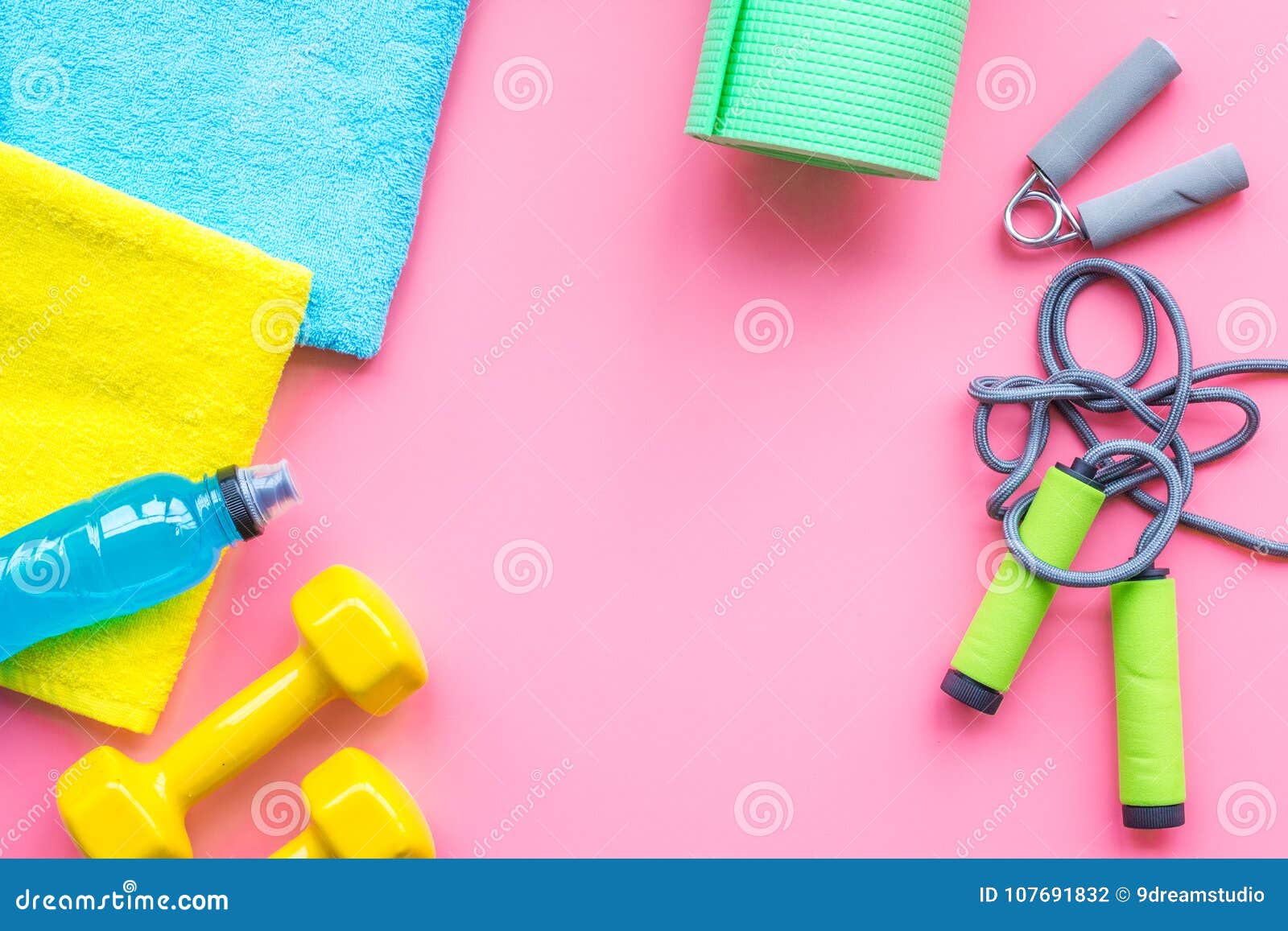 Fitness background. Equipment for gym and home. Jump rope, dumbbells,  expander, water on pastel pink background top view copy space Stock Photo