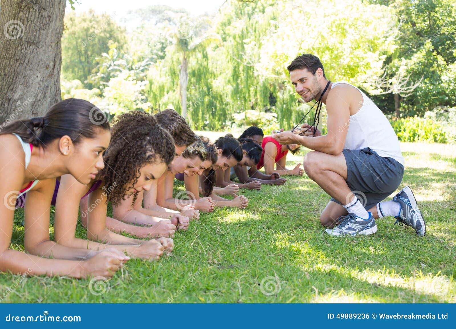 fitness group planking in park with coach