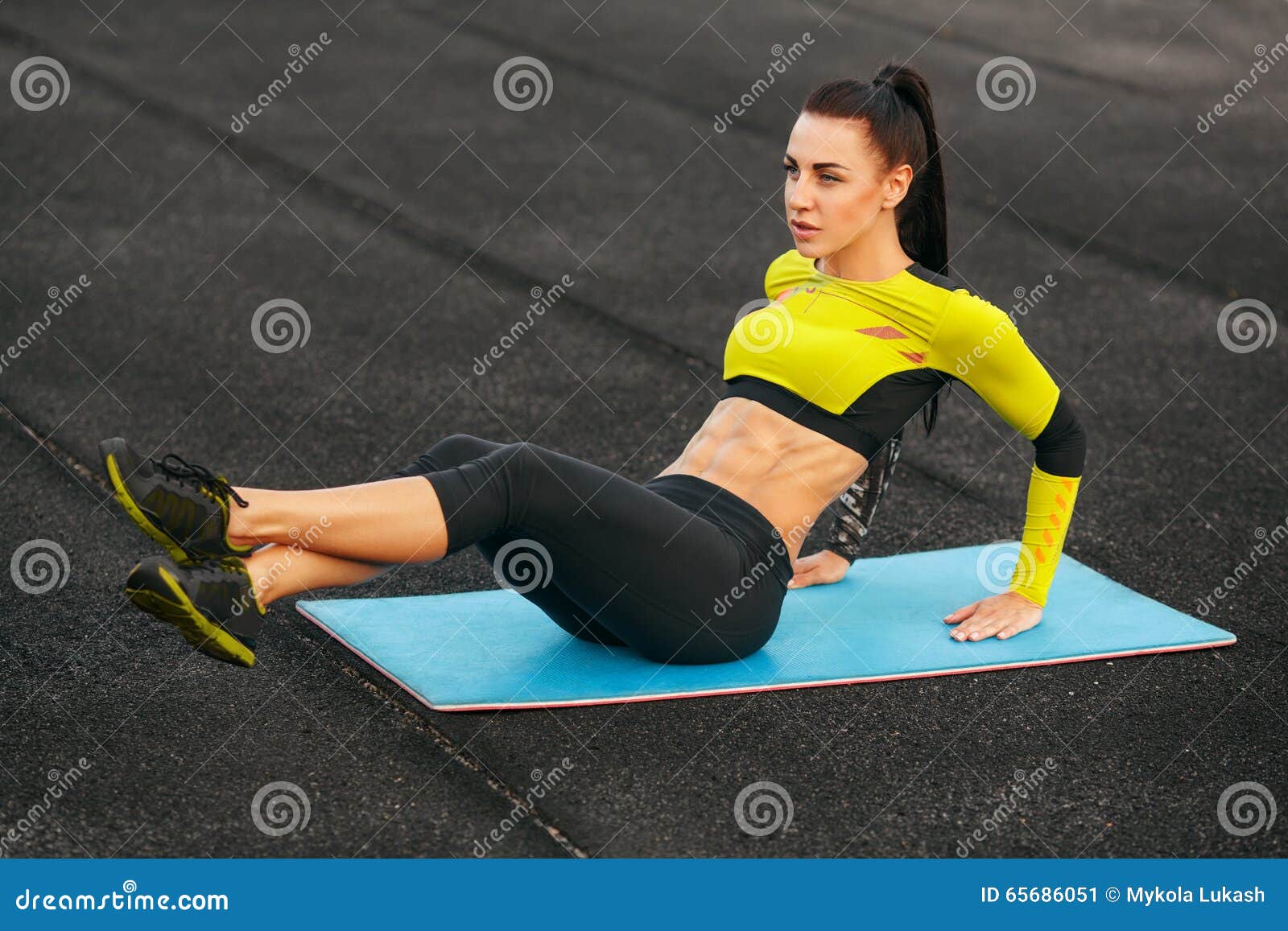 fitness woman doing sit ups in the stadium working out. sporty girl exercising abdominals, outdoor