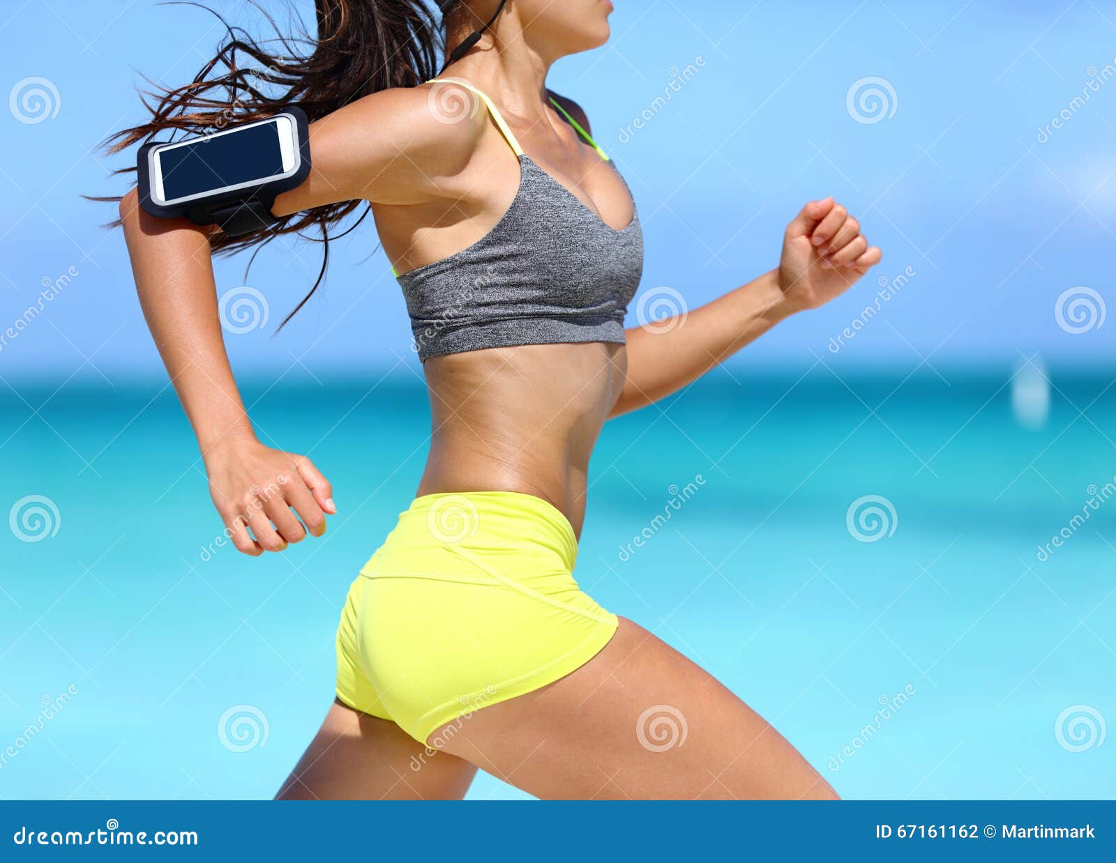 Female runner on beach with sports bra and shorts. Midsection closeup of  body of a woman athlete running with speed fast training cardio wearing  neon yellow activewear outfit. Active lifestyle. Photos