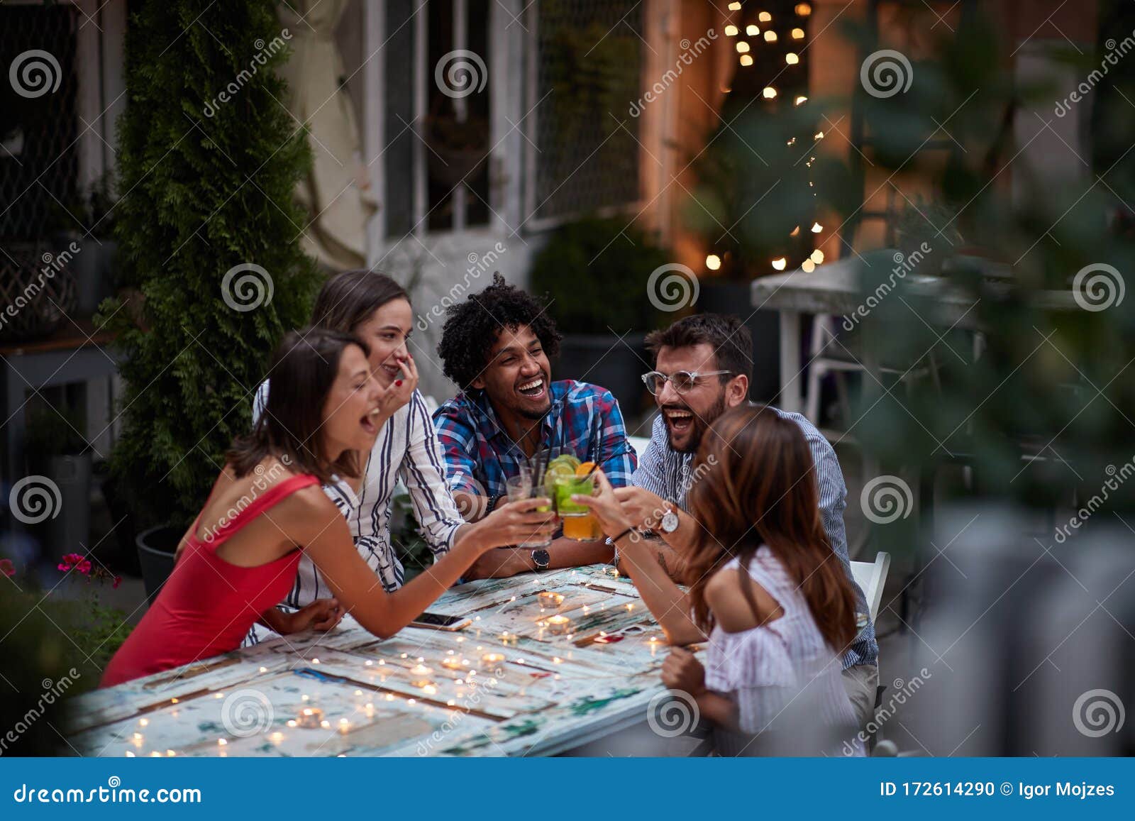 group of five adults making toast with cocktails, at the outdoor bar, laughing, having fun. fun, party, socializing, multiethnic,