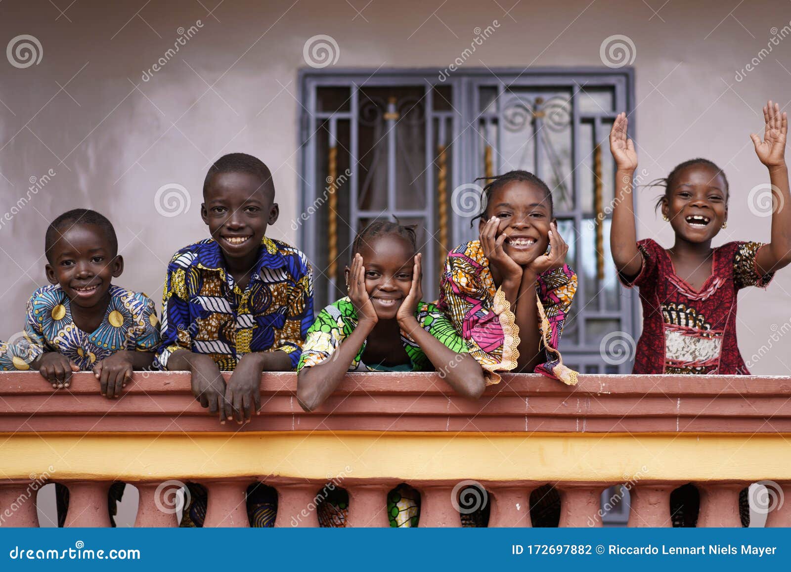 five african children greeting bypassers from a colonial house balcony