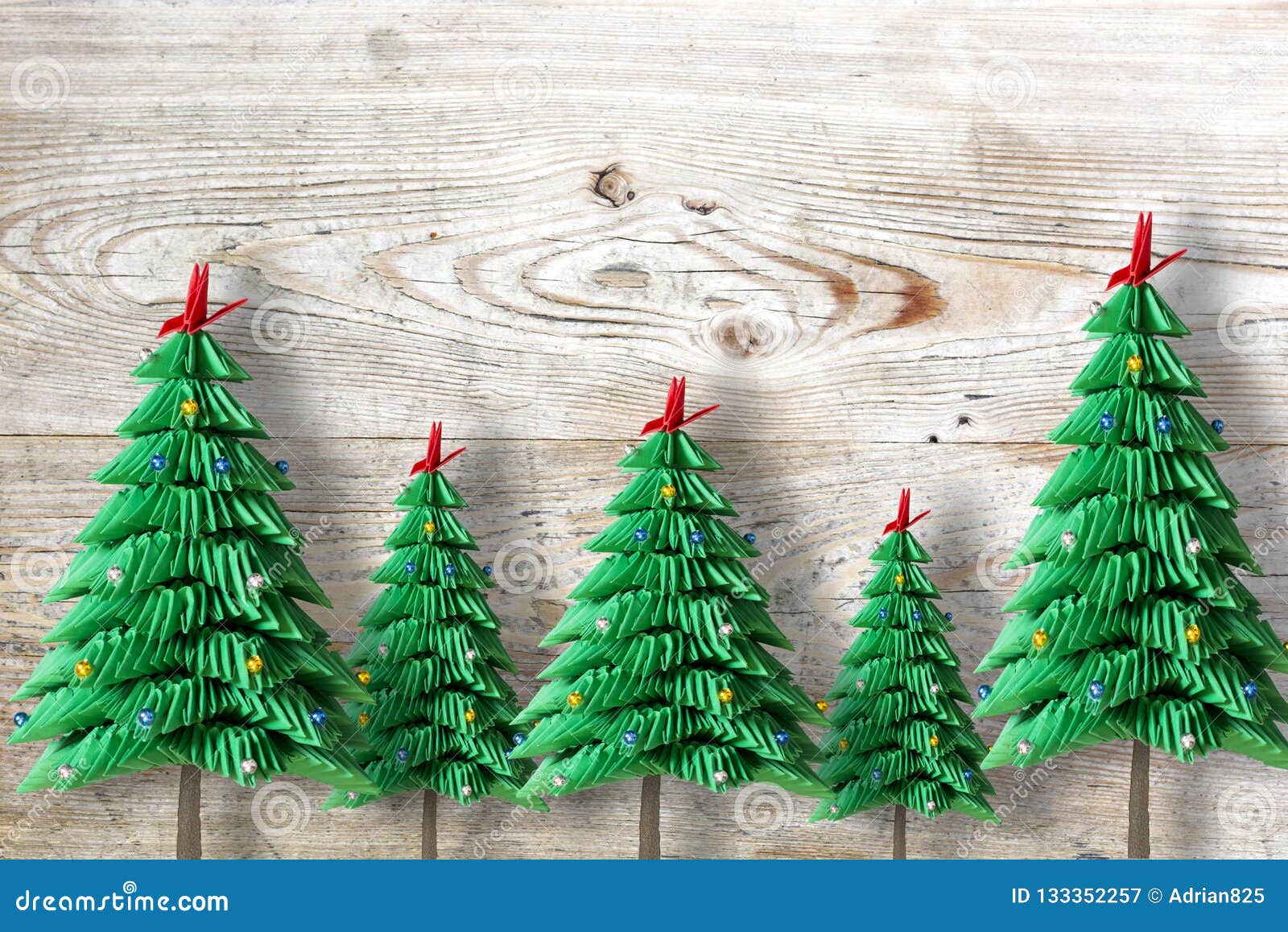 Five Christmas Trees from Green Folded Paper or Origami on Wooden