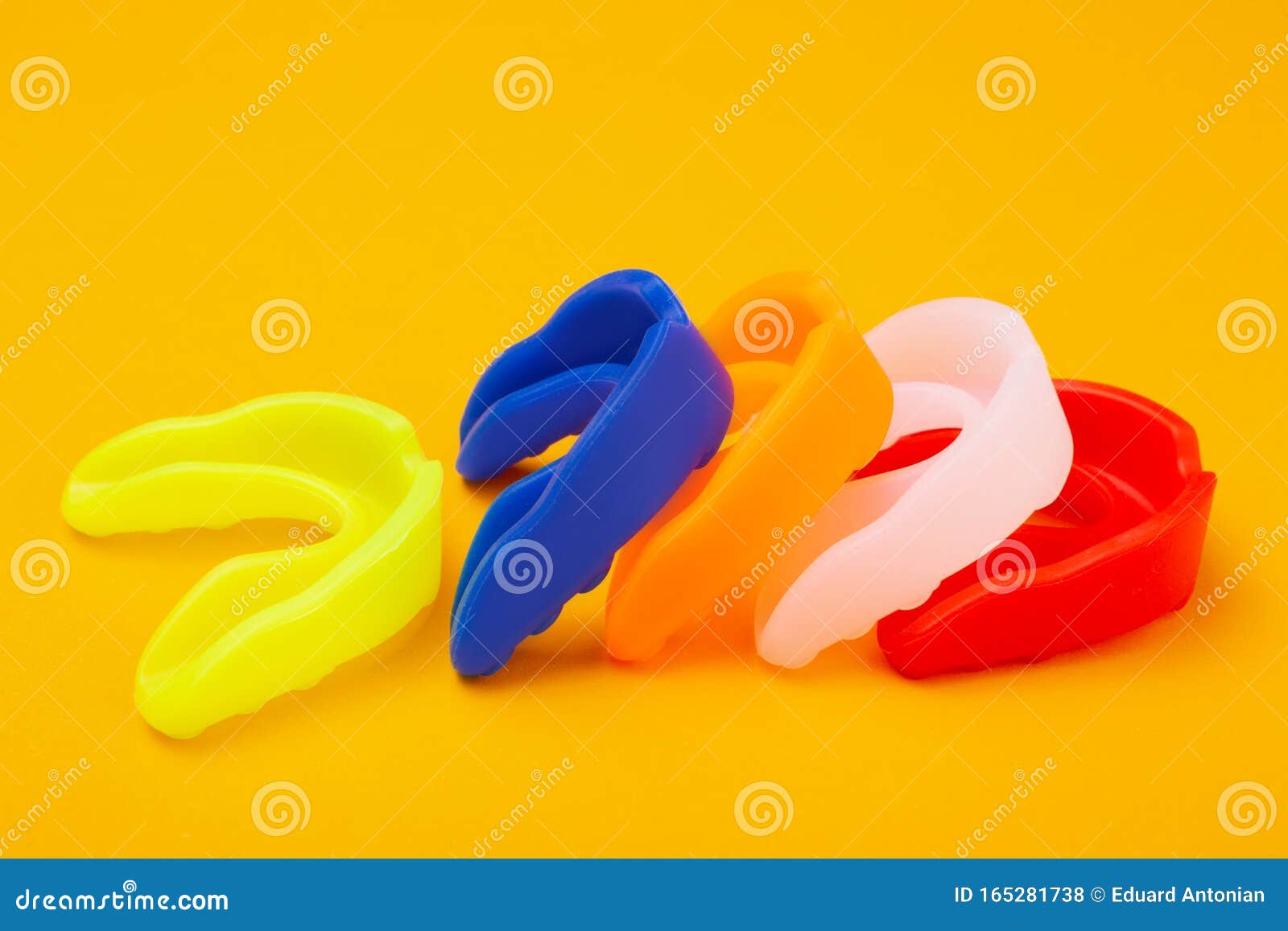 five colored boxing mouth guards laid out in a row on a yellow background, concept