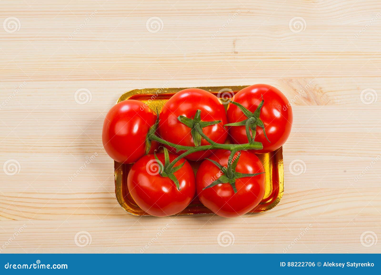 Five fresh red tomatoes with green stem in the tray , isolated on the background.
