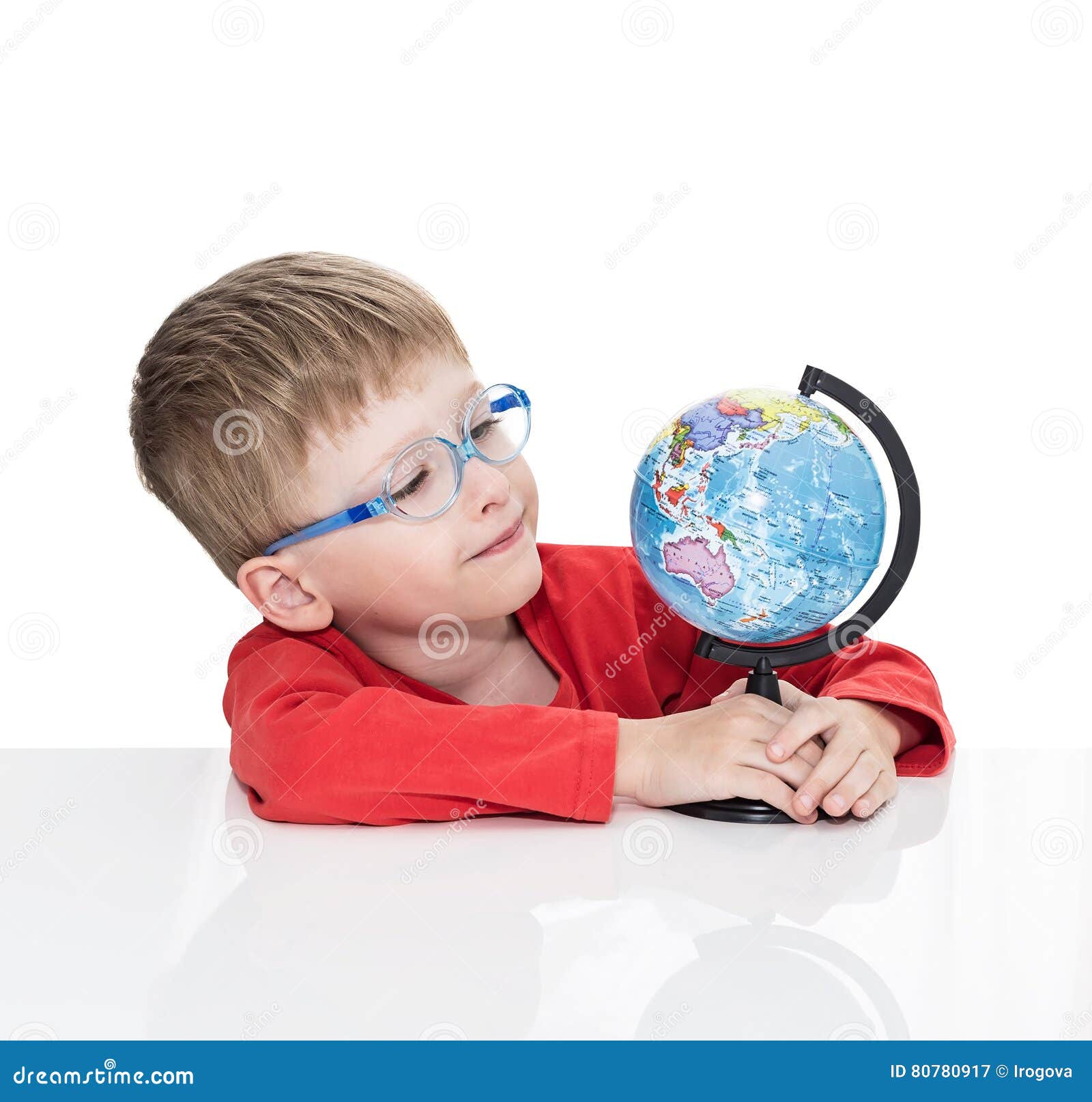 The Fiveyearold Boy in Blue Points Sits at a White Table and Holds the Globe in Hand Stock