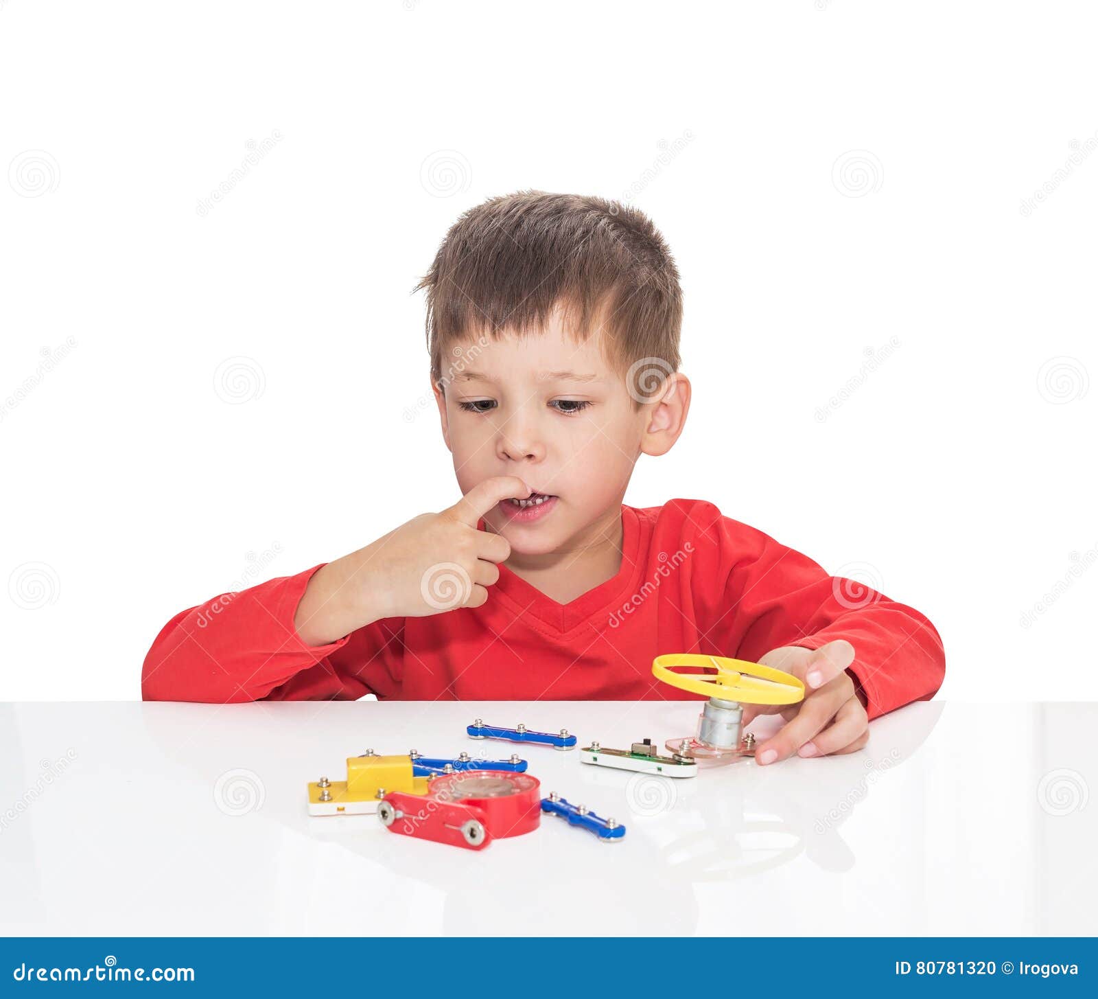 The Fiveyearold Boy Sits at a White Table and Plays an Electronic Designer Stock Photo Image